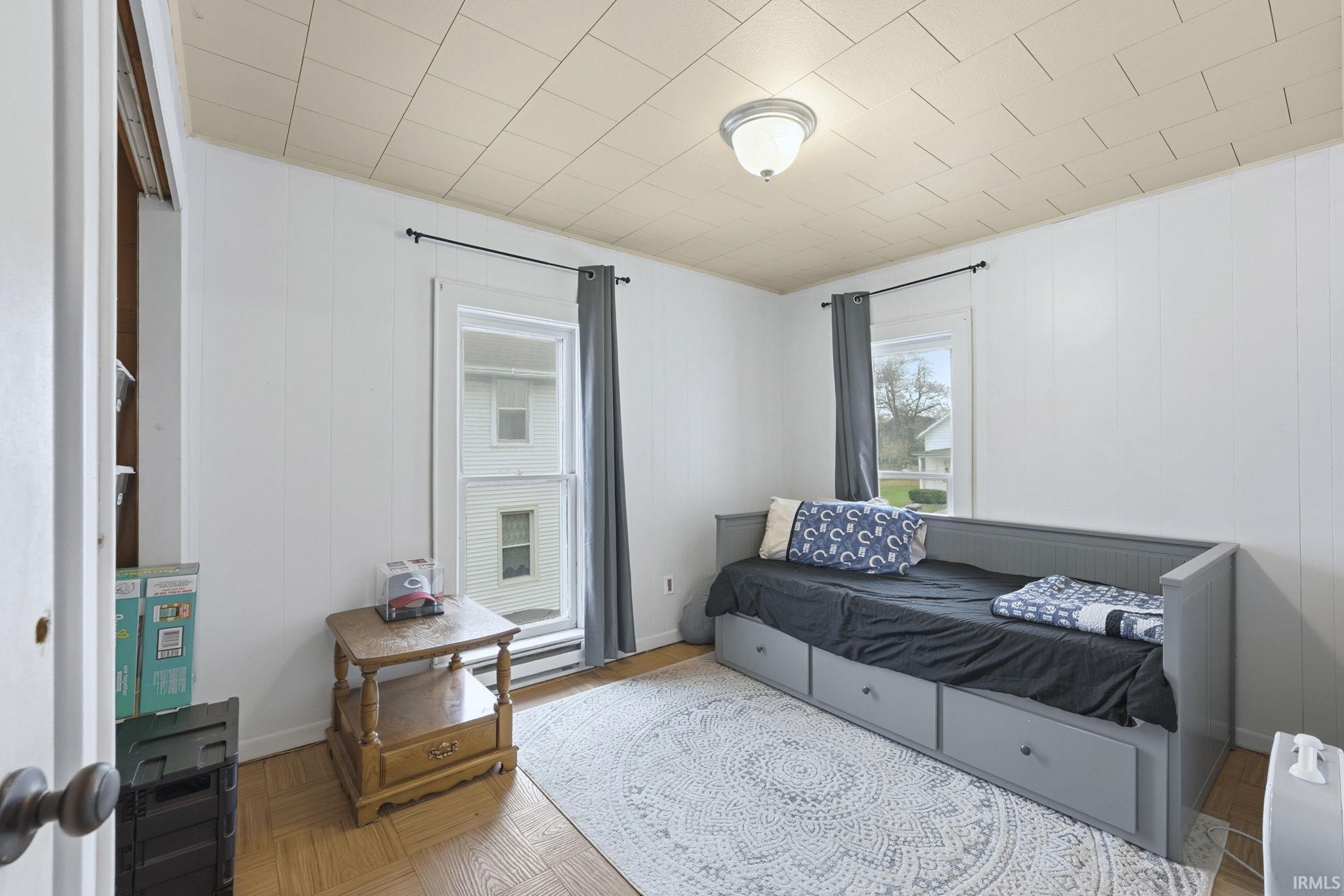 Bedroom featuring wood walls and parquet floors