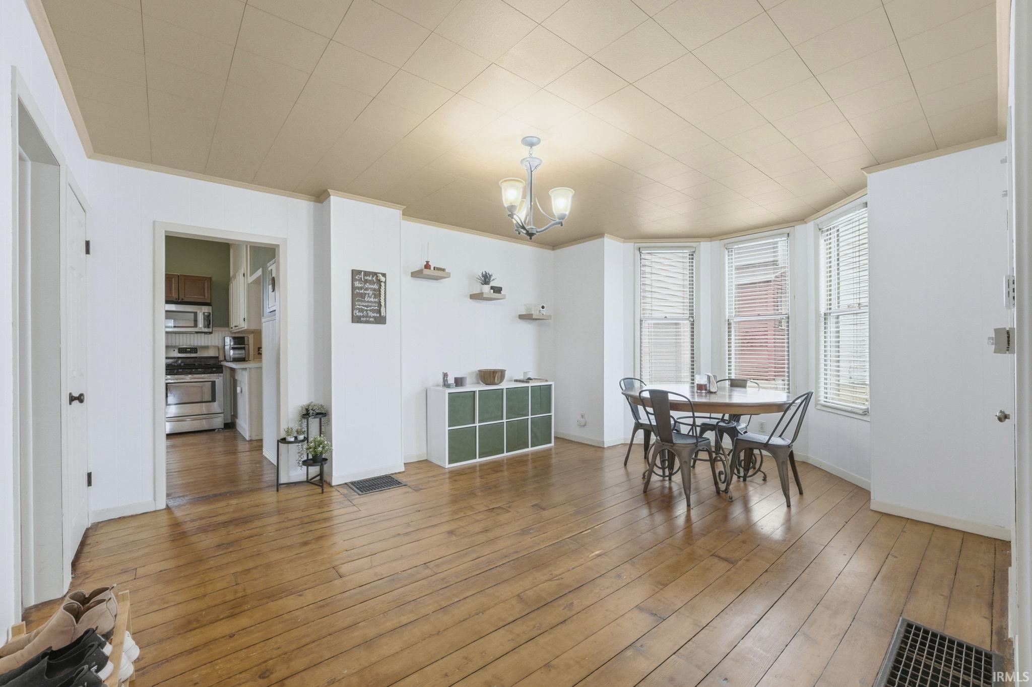 Dining room featuring light wood-style floors, a chandelier, and crown molding