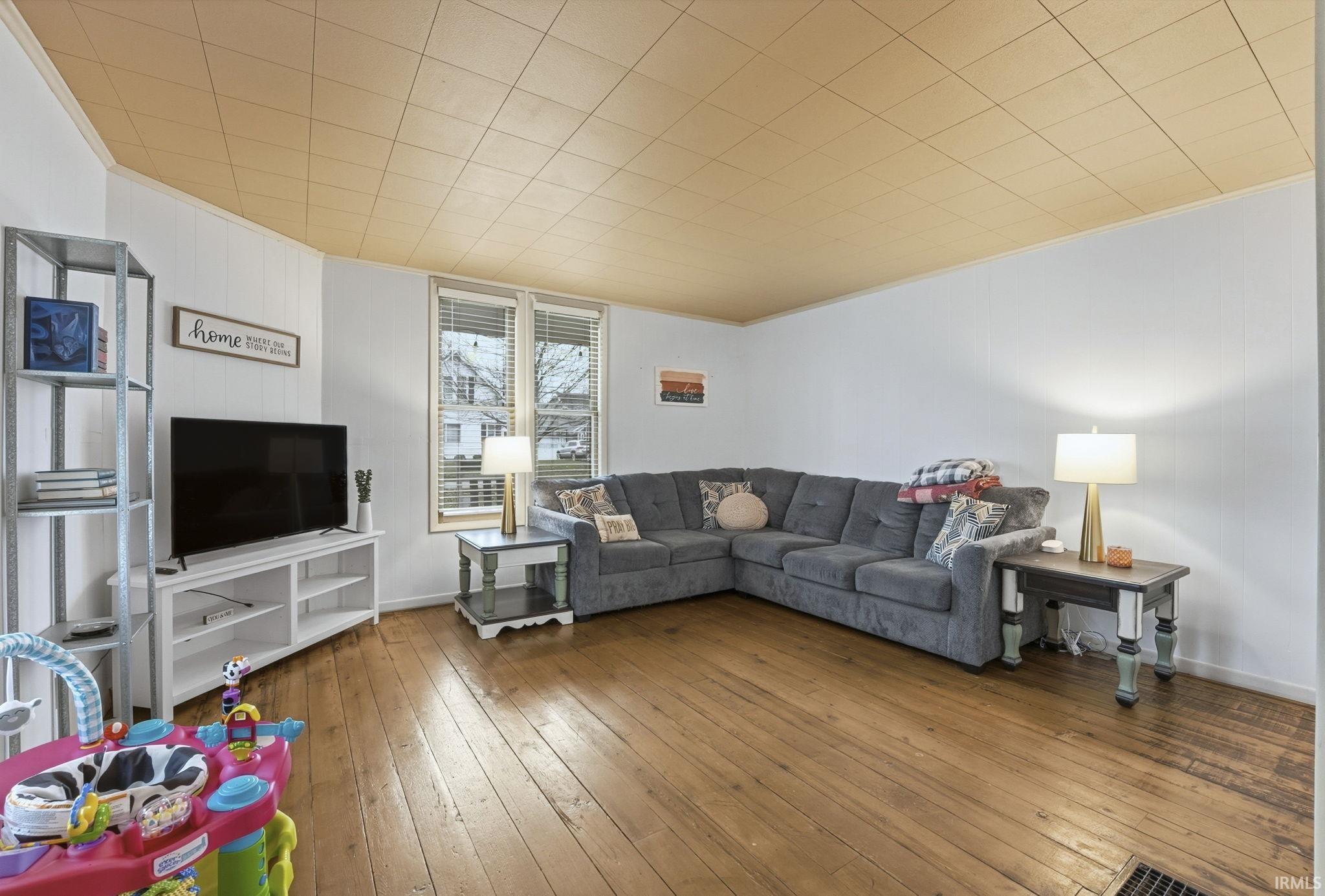 Living room featuring hardwood / wood-style floors, crown molding, and wood walls