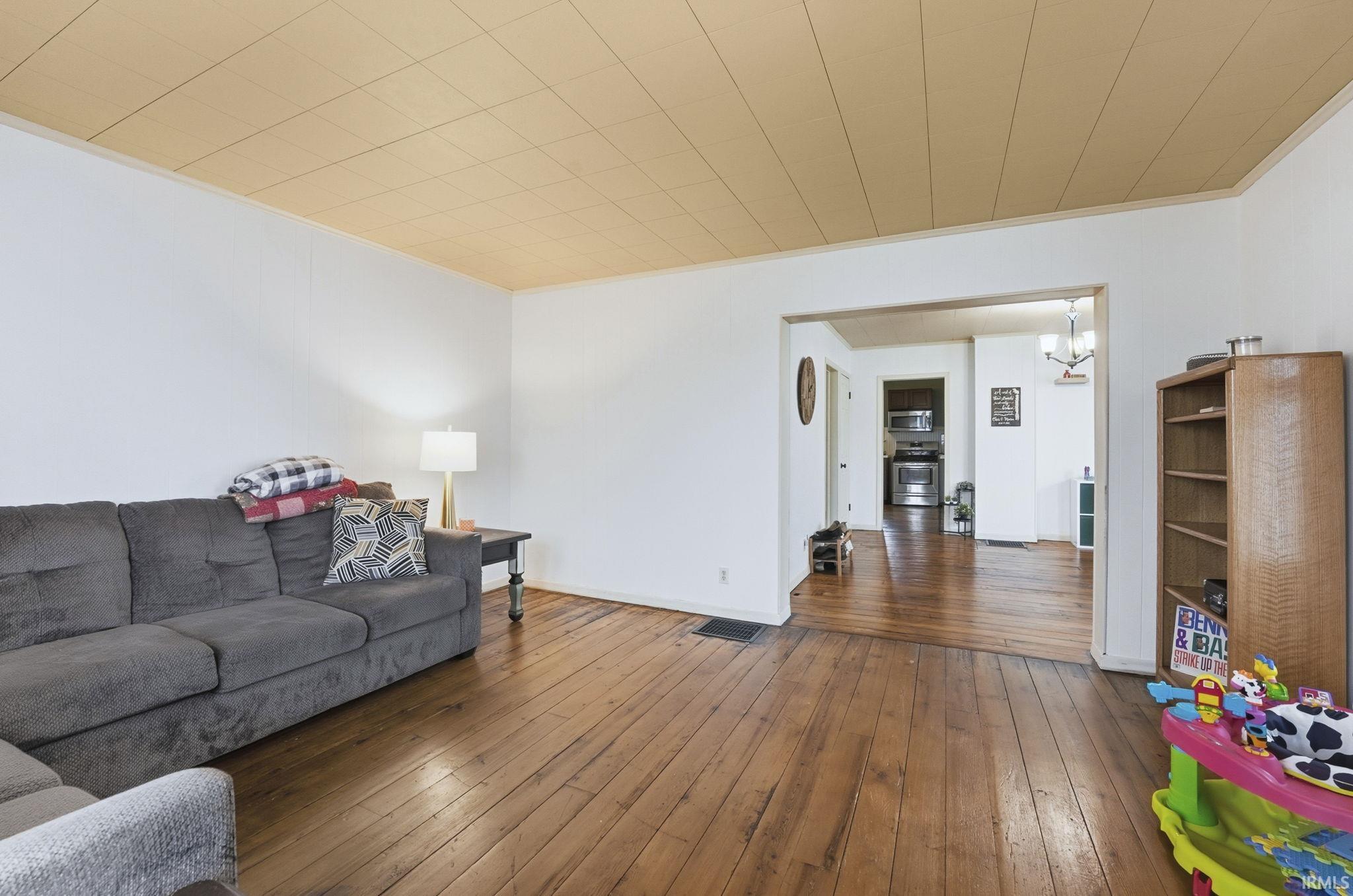 Living room featuring hardwood / wood-style flooring, a chandelier, and ornamental molding