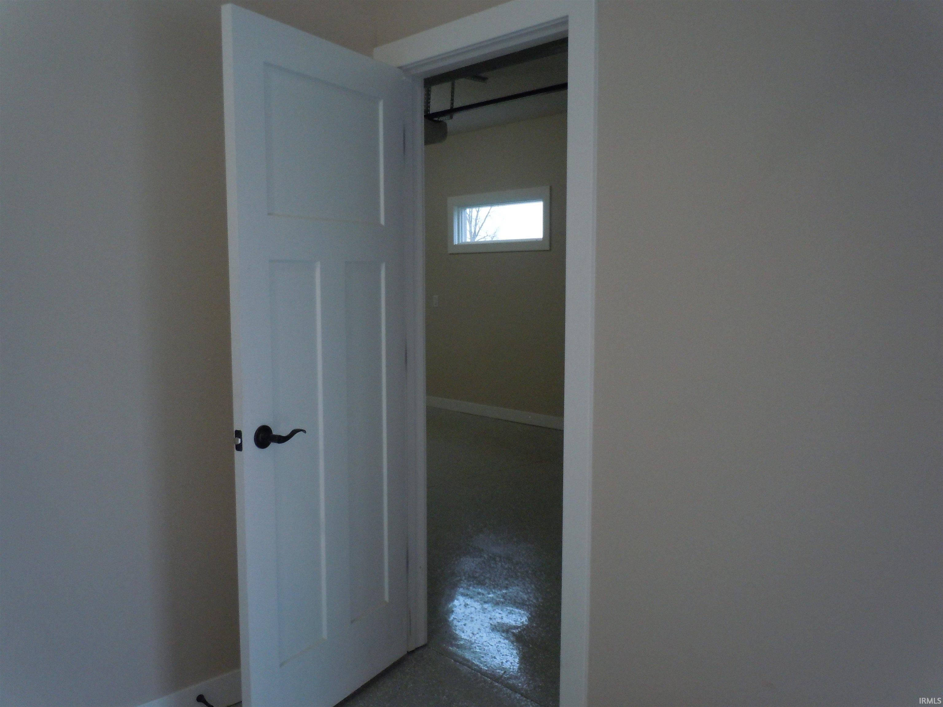 Hallway with finished concrete flooring and baseboards