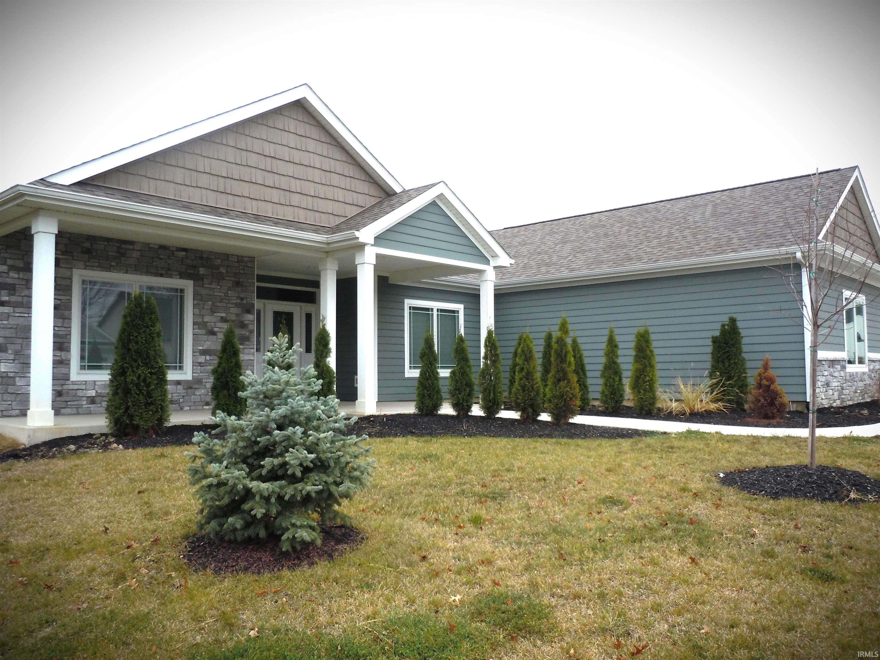 View of front of property featuring a front lawn, stone siding, and a shingled roof