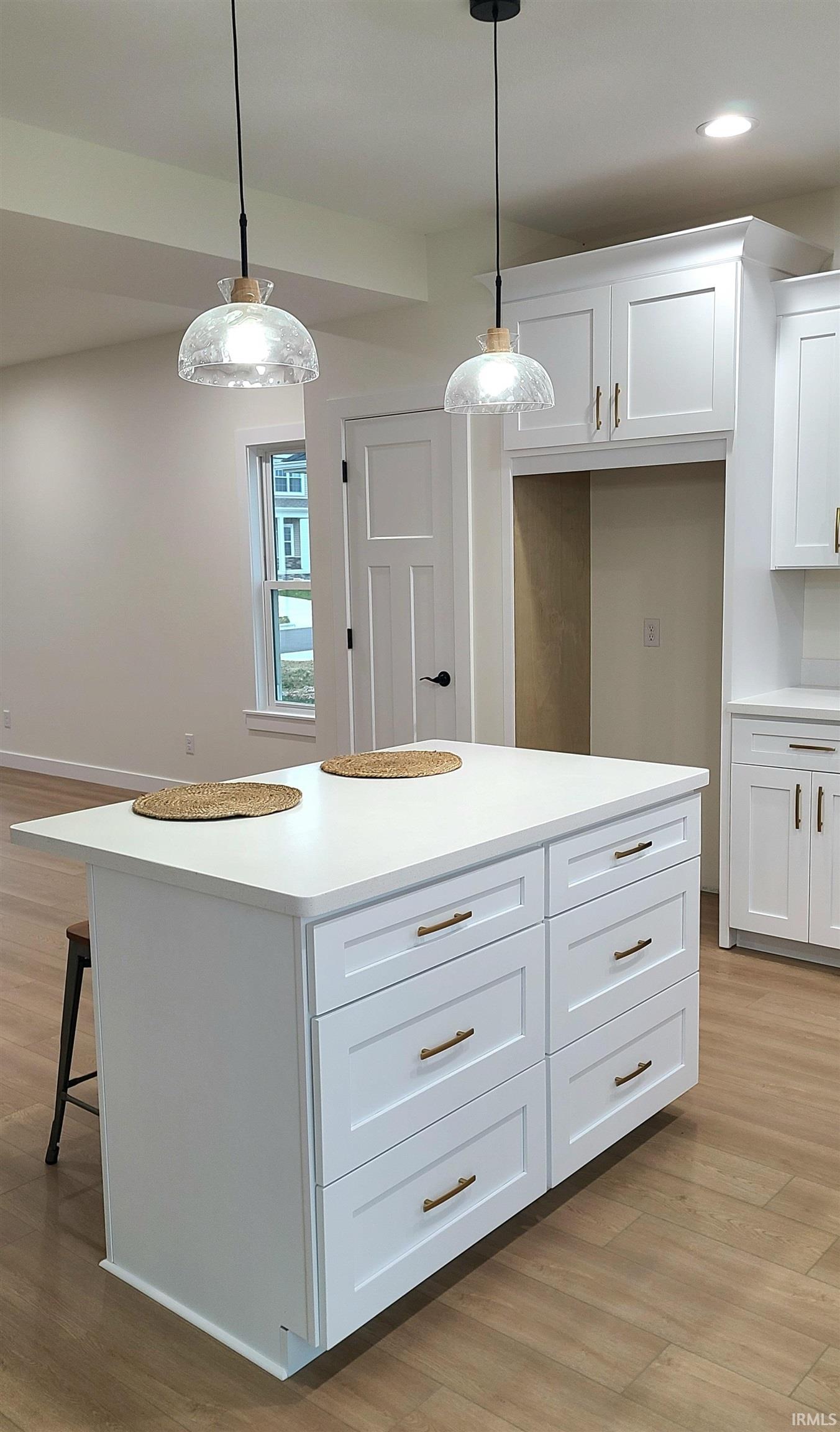 Kitchen featuring light wood-style flooring, hanging light fixtures, white cabinets, and recessed lighting
