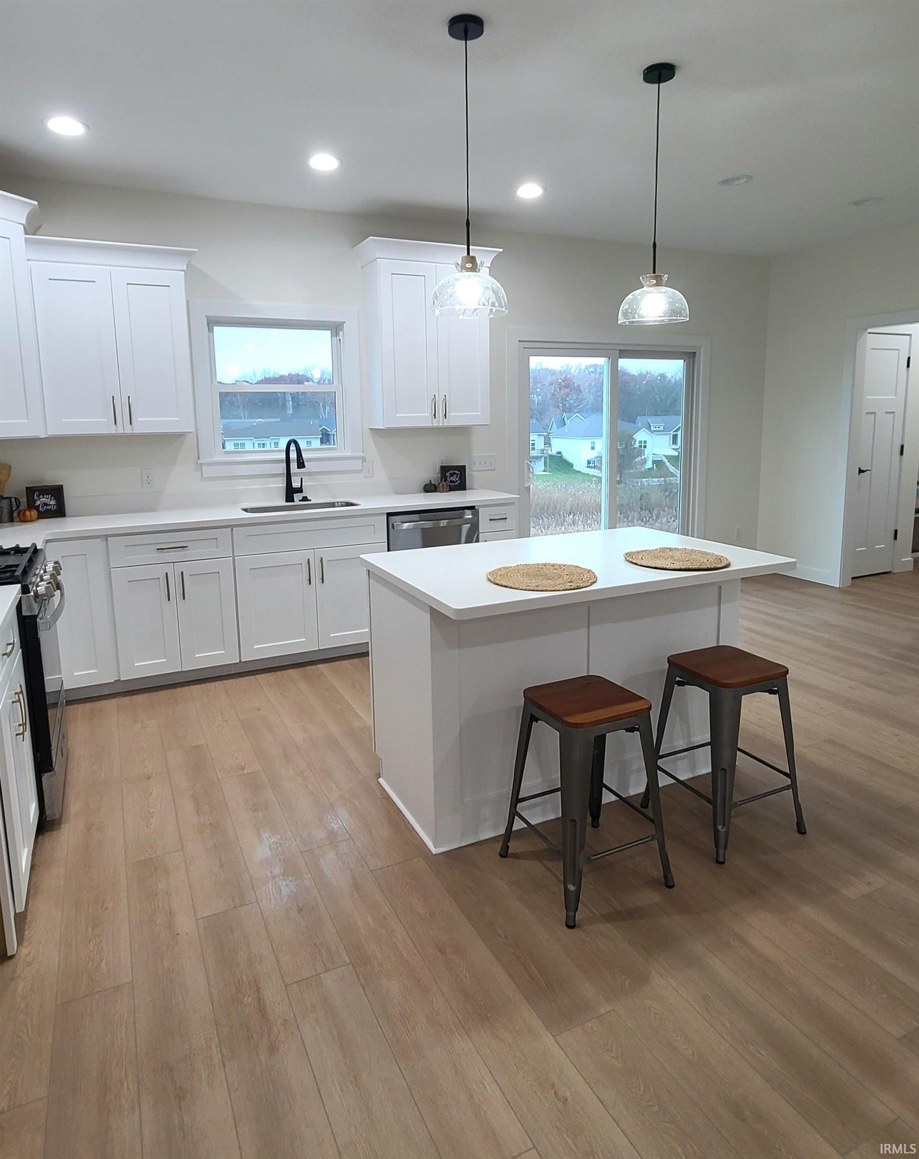 Kitchen with a breakfast bar, pendant lighting, white cabinetry, healthy amount of natural light, and recessed lighting