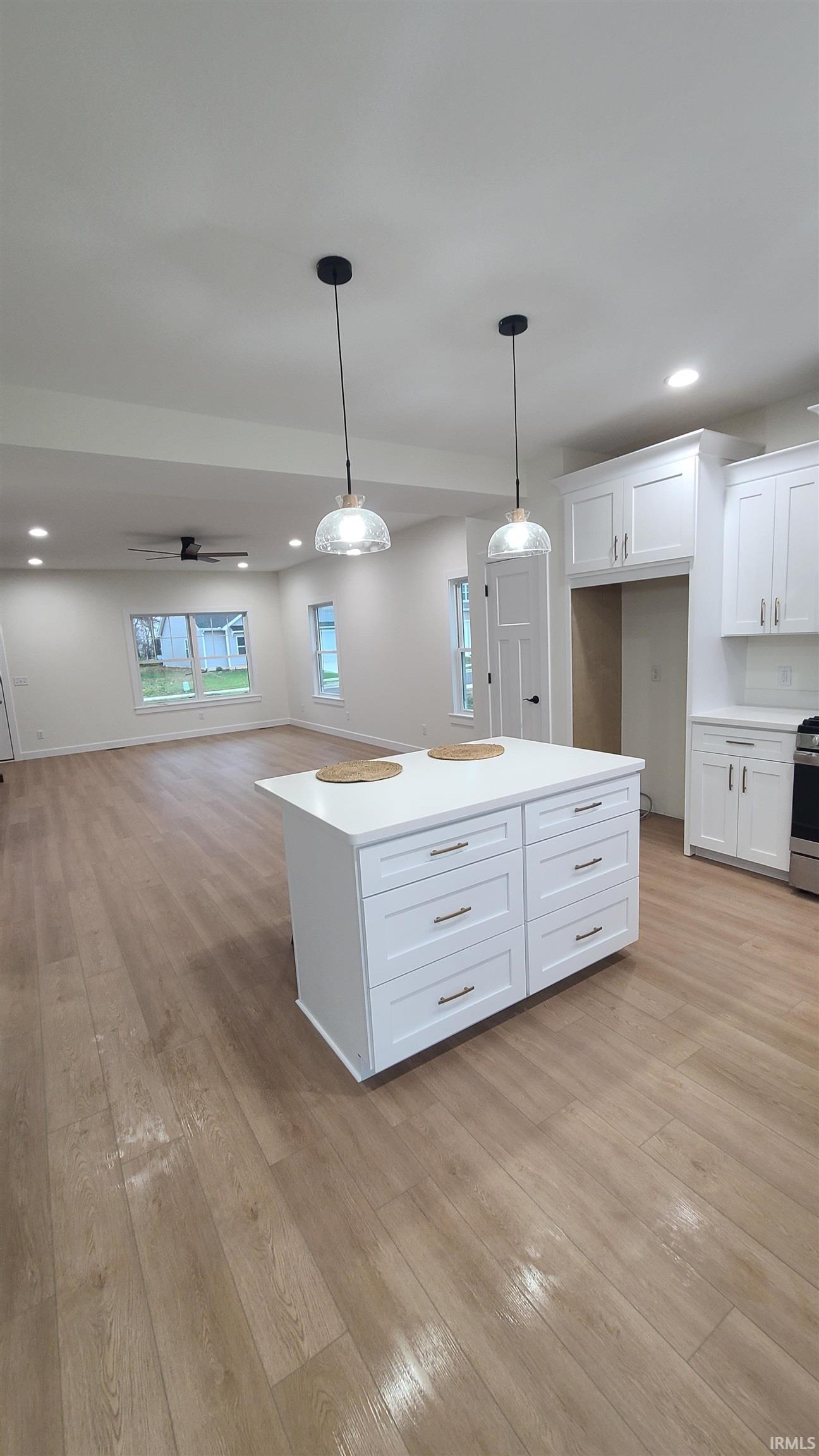 Kitchen featuring white cabinetry, pendant lighting, recessed lighting, light wood-style floors, and open floor plan