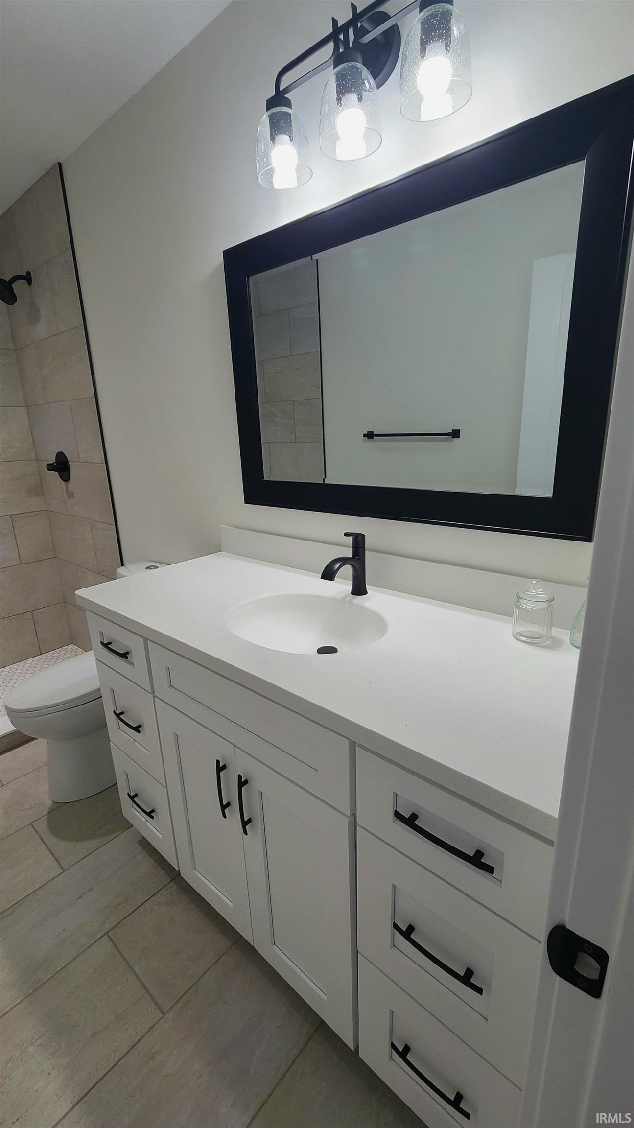Full bathroom with vanity, a tile shower, and light tile patterned floors