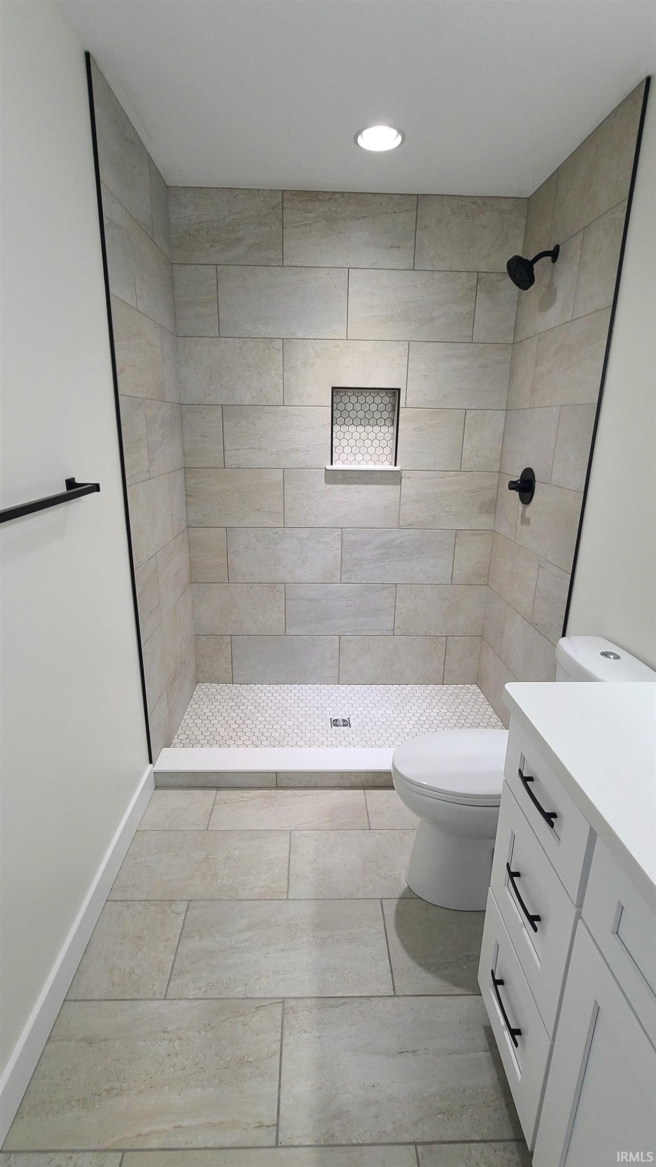 Bathroom featuring a shower stall, vanity, light tile patterned floors, and recessed lighting
