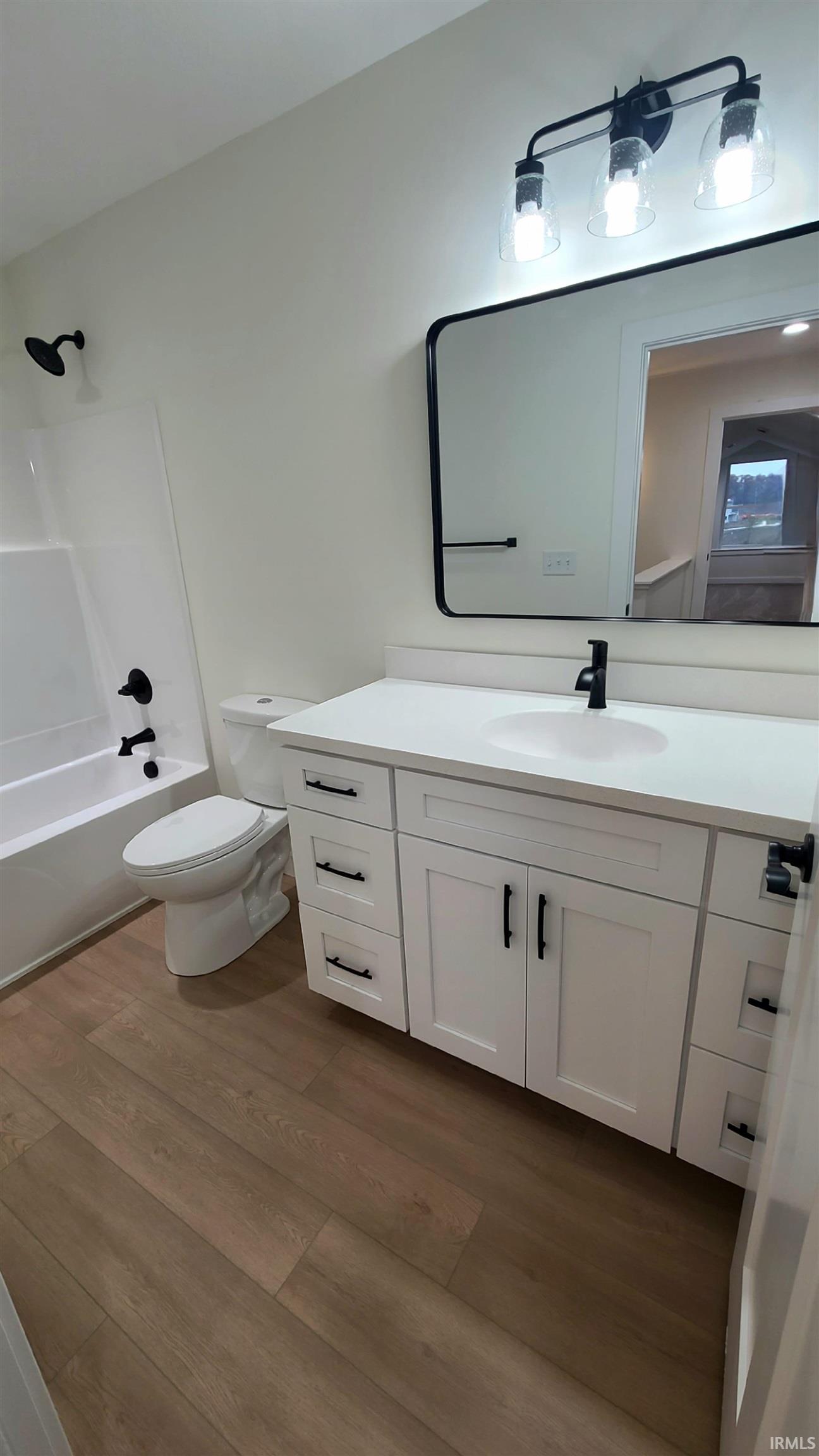 Full bathroom featuring vanity,  shower combination, and dark wood-style floors