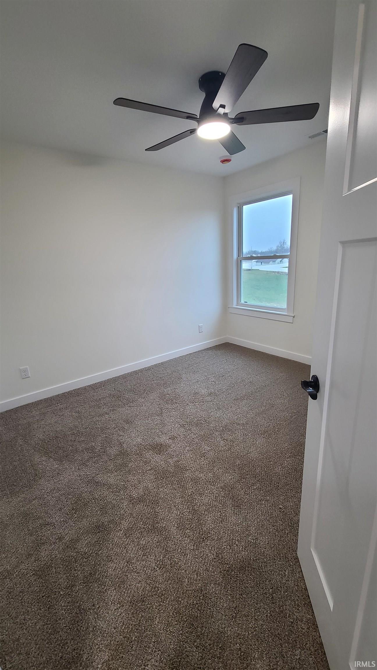 Spare room featuring dark carpet and baseboards