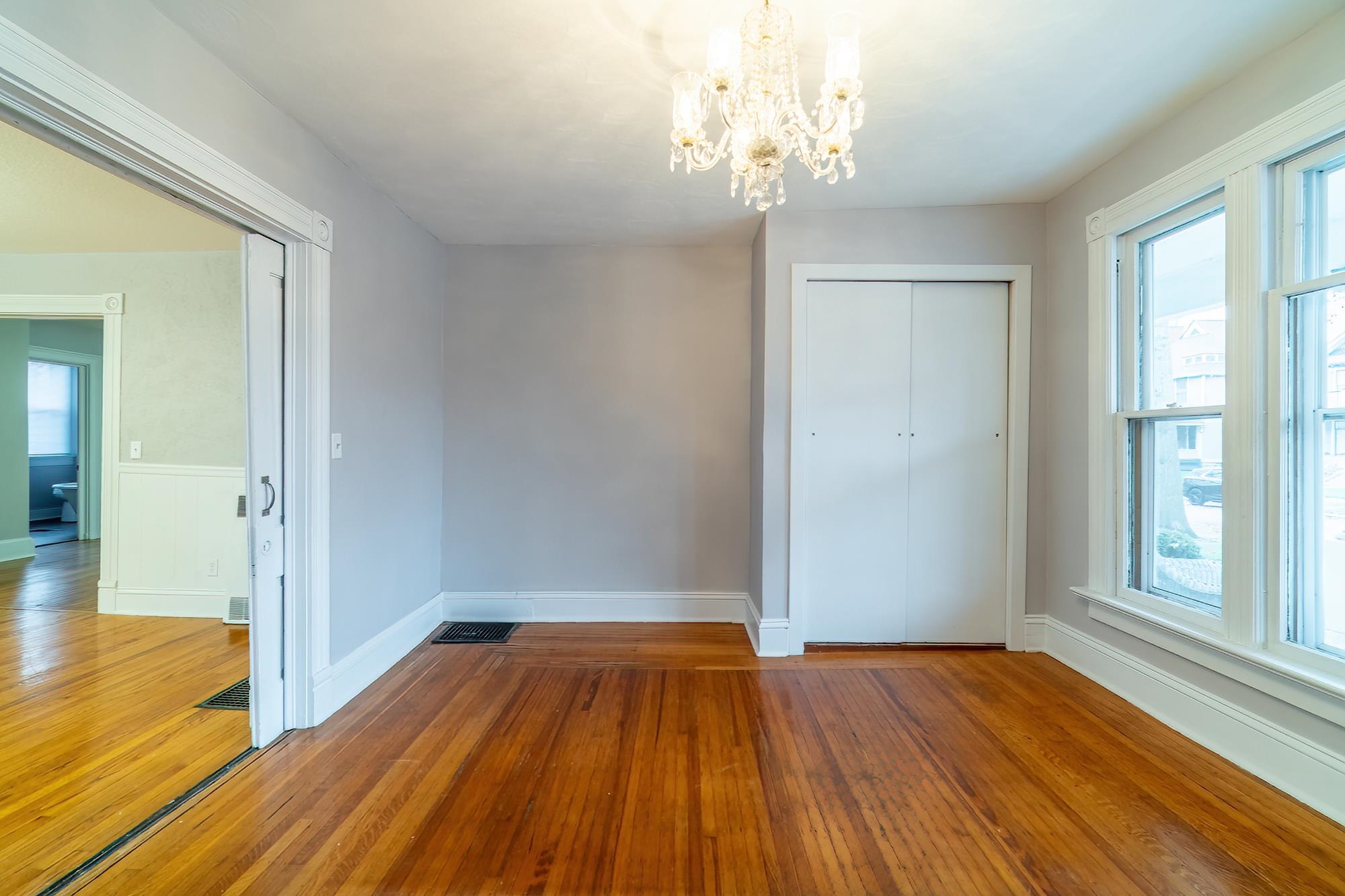 Unfurnished bedroom featuring wood finished floors, a closet, and a chandelier