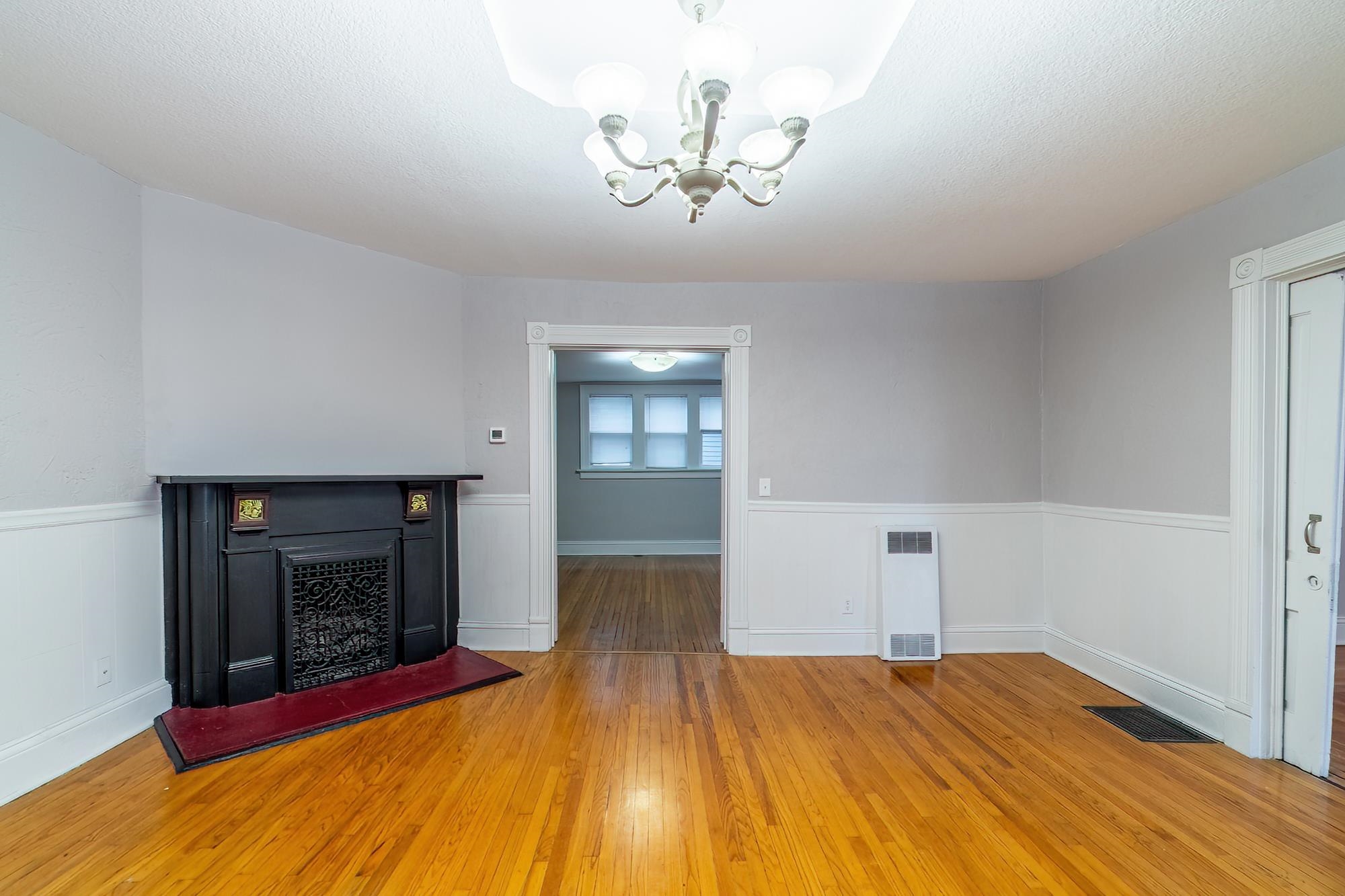 Unfurnished living room with wood finished floors, a chandelier, and a fireplace