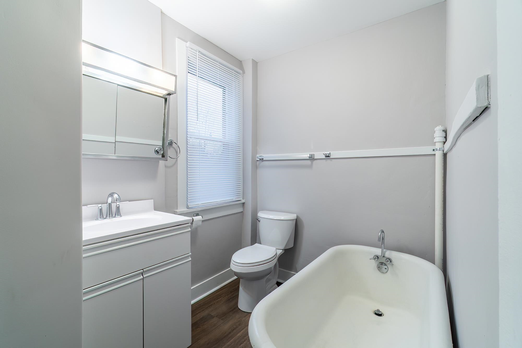 Full bathroom featuring a soaking tub, vanity, and dark wood-style flooring