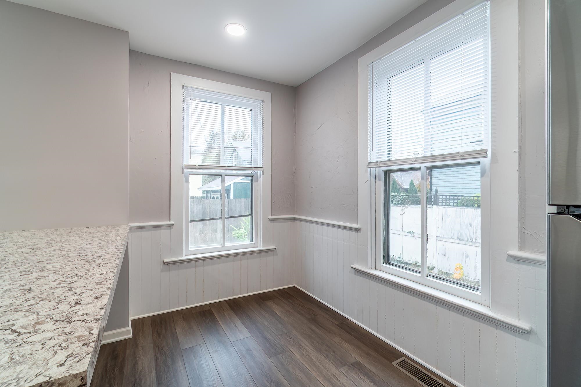Spare room featuring wainscoting and dark wood-type flooring