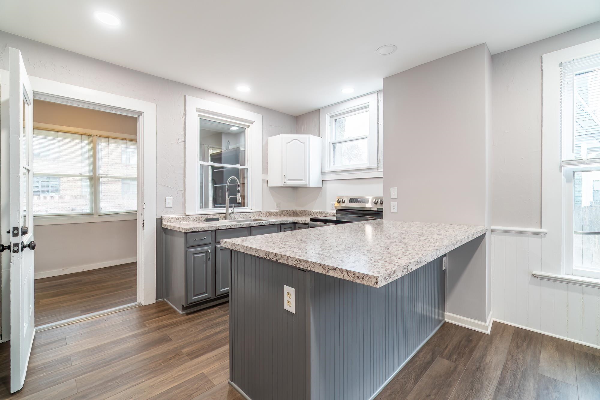 Kitchen featuring healthy amount of natural light, dark wood-style flooring, gray cabinets, a peninsula, and recessed lighting