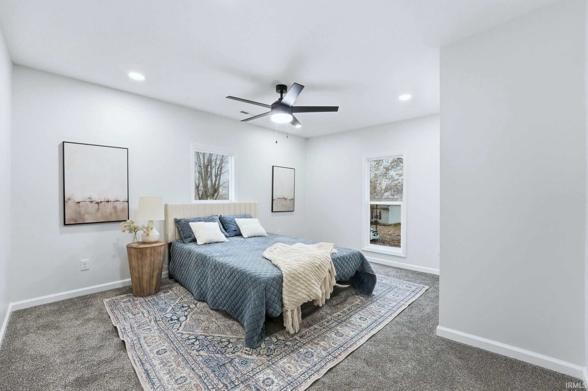 Carpeted bedroom with a ceiling fan and recessed lighting
