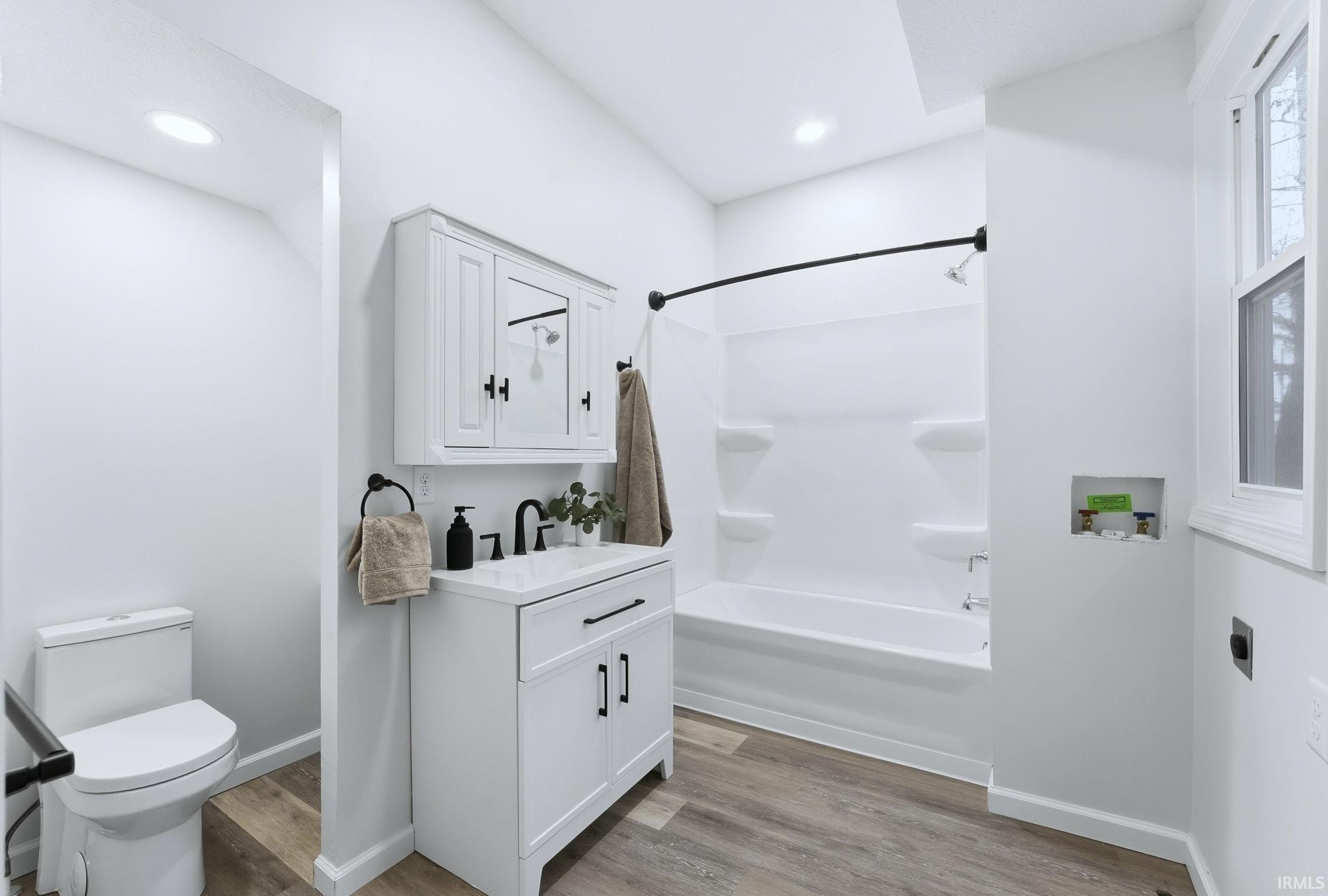 Full bath with vanity, shower / bath combo with shower curtain, light wood-style flooring, and recessed lighting