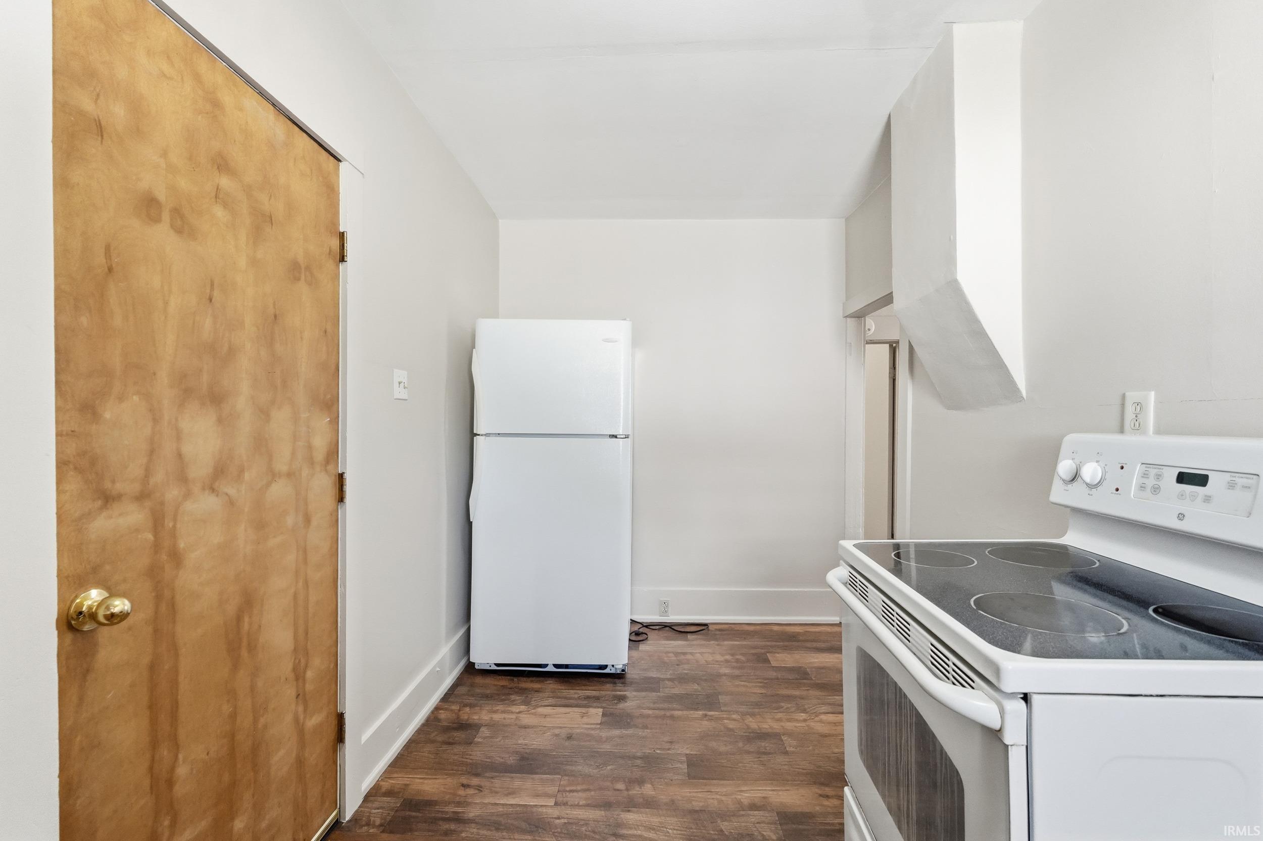 Kitchen featuring white appliances and dark wood-type flooring