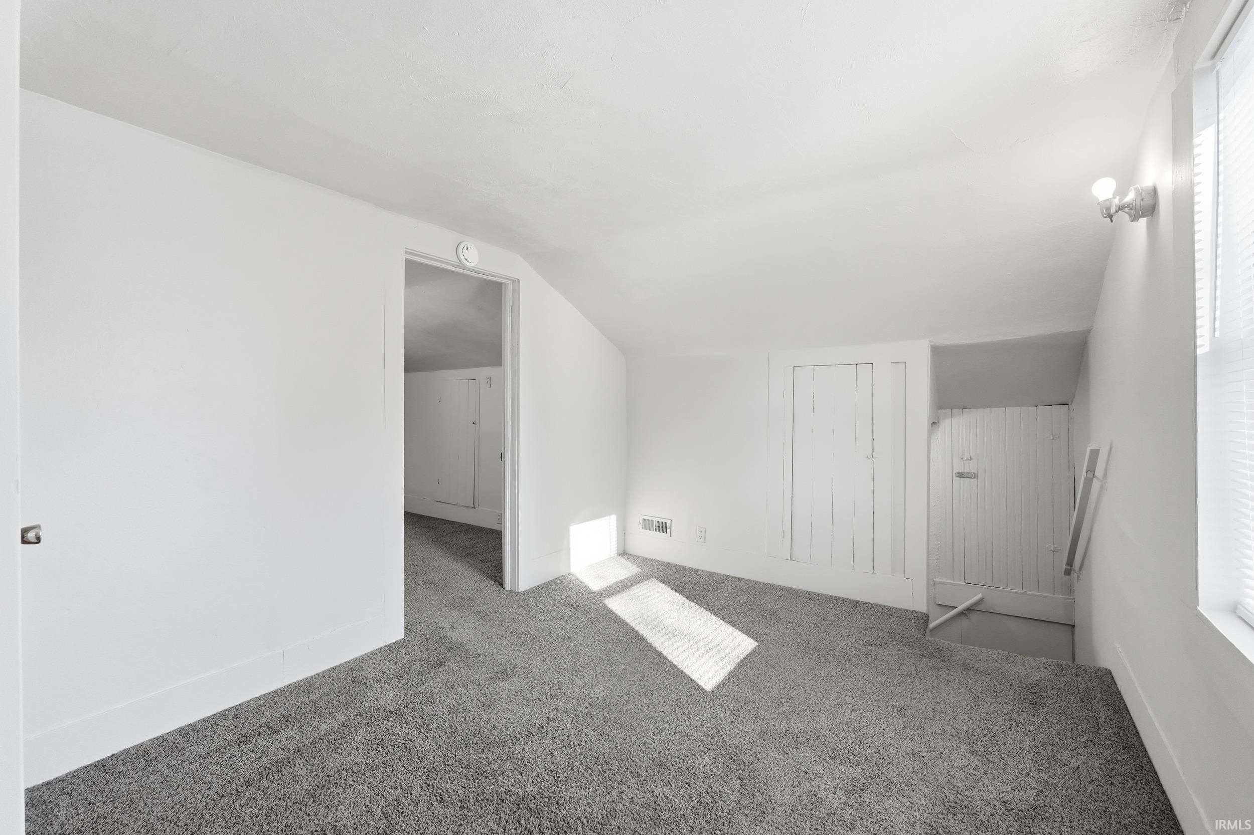 Additional living space featuring lofted ceiling, carpet floors, and plenty of natural light