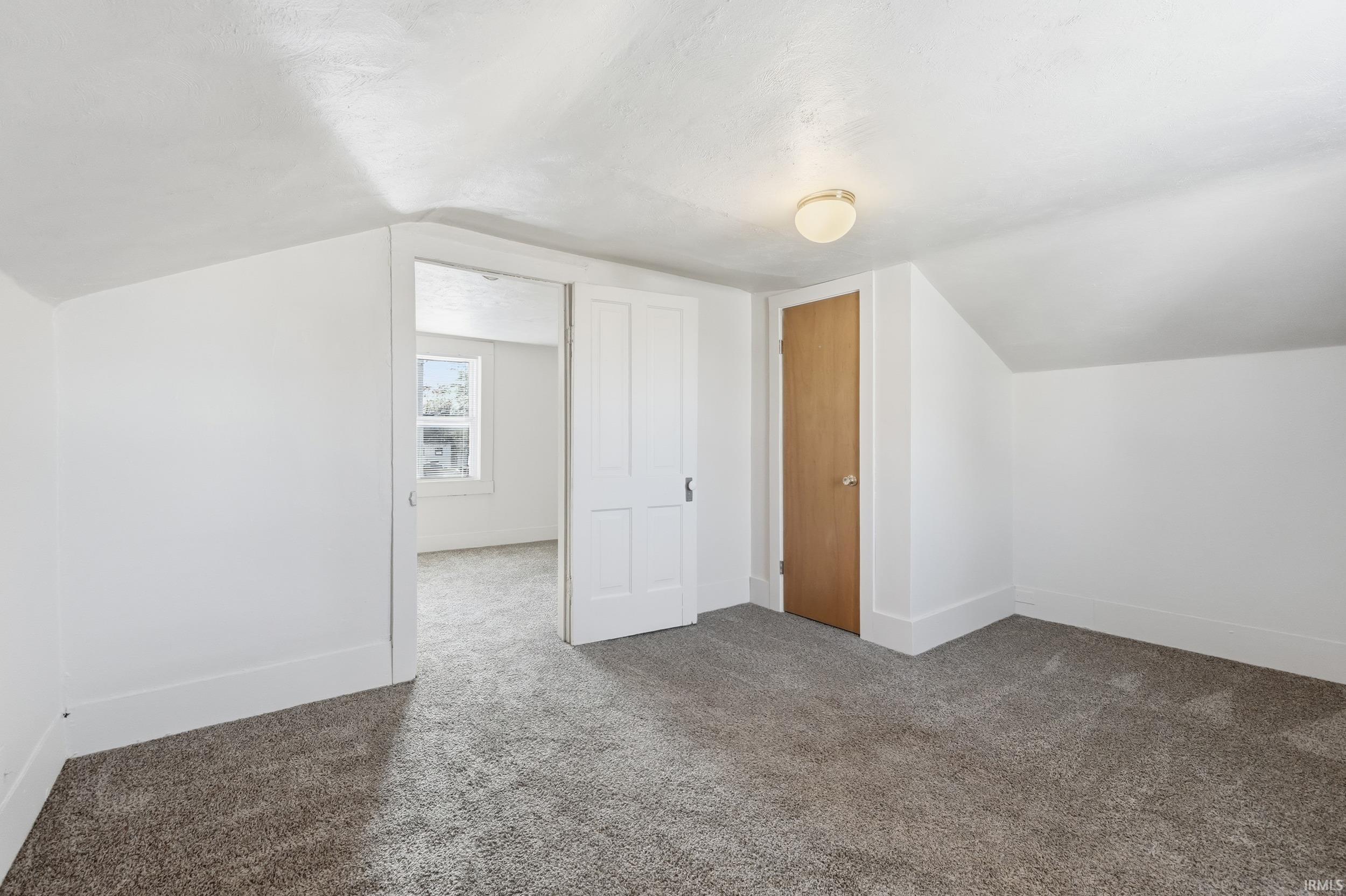 Additional living space with vaulted ceiling and carpet floors