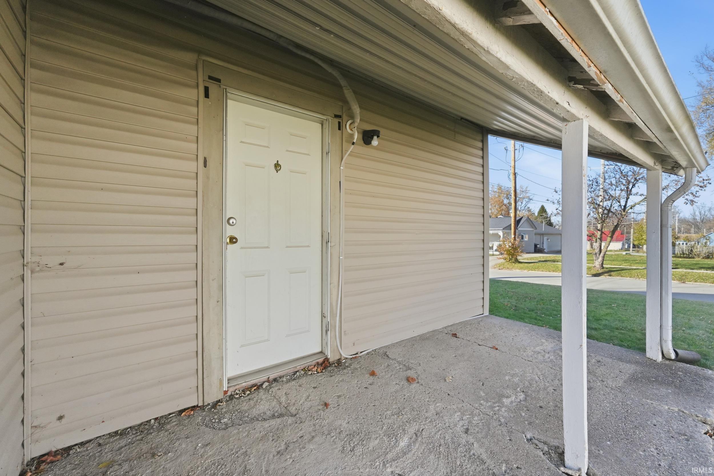 View of exterior entry with a yard and covered porch
