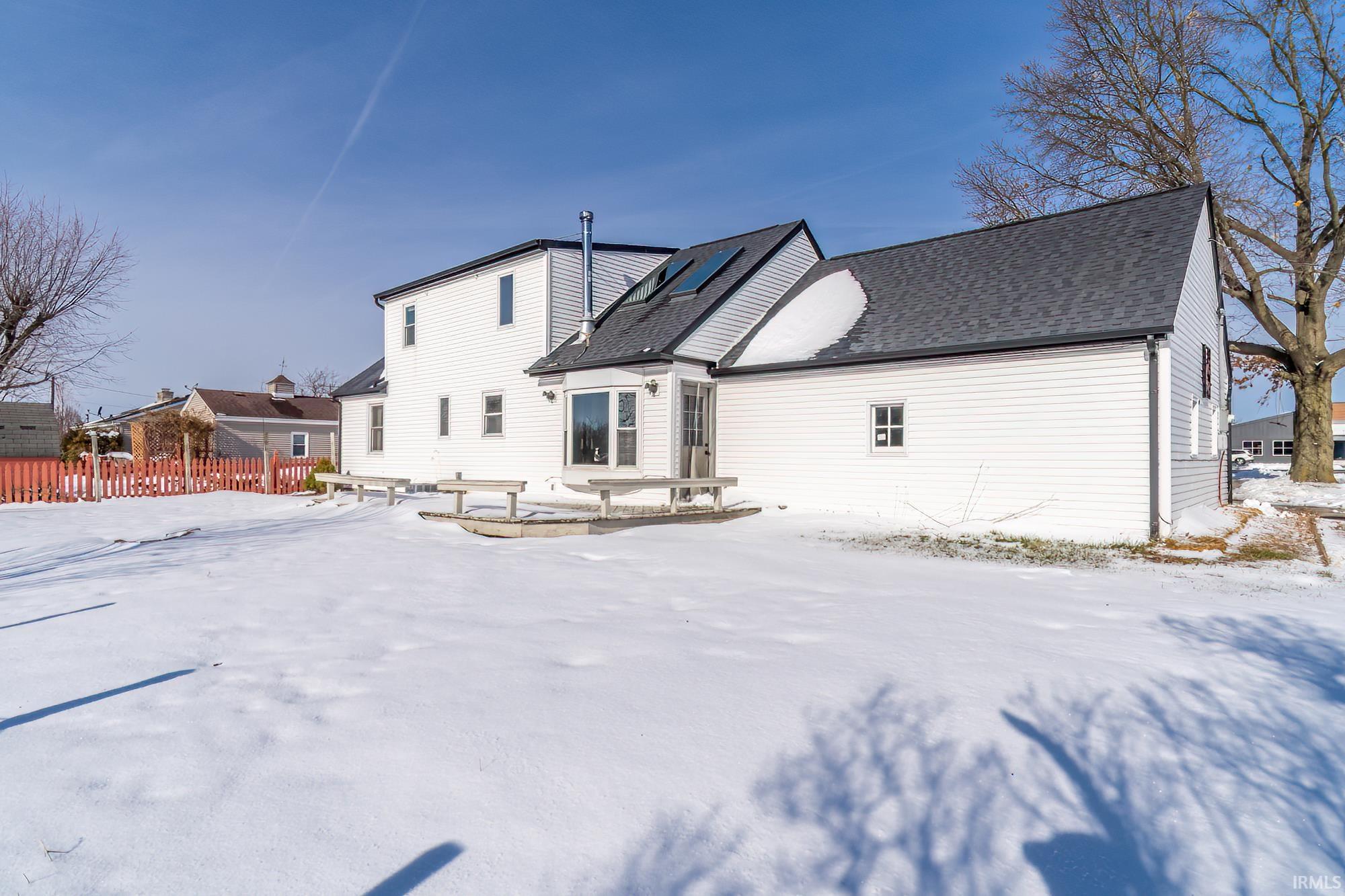 Snow covered back of property with roof with shingles