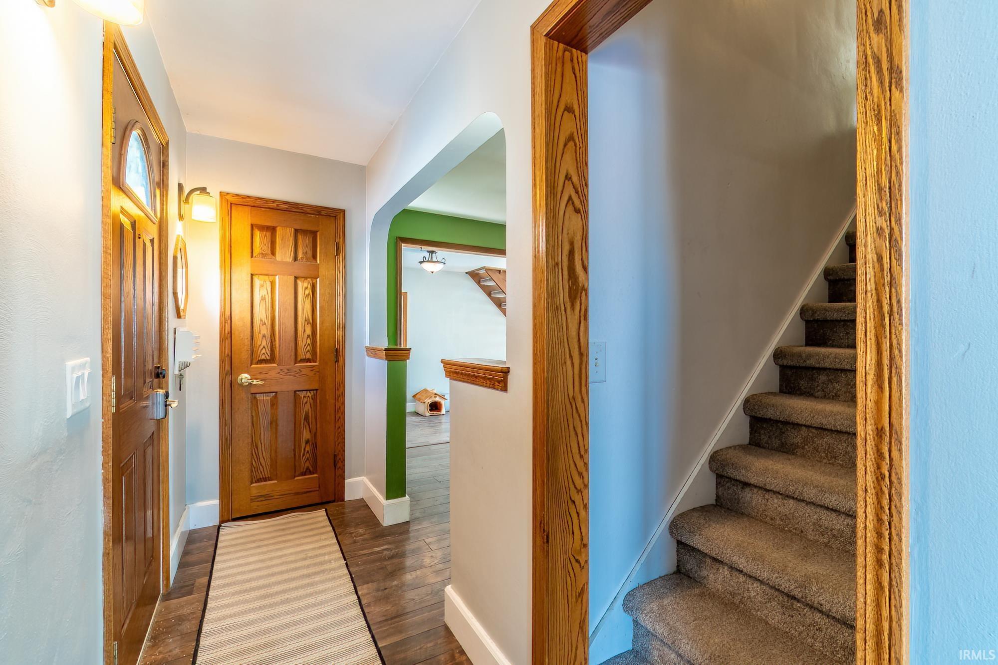 Entrance foyer featuring stairs and dark wood-style flooring