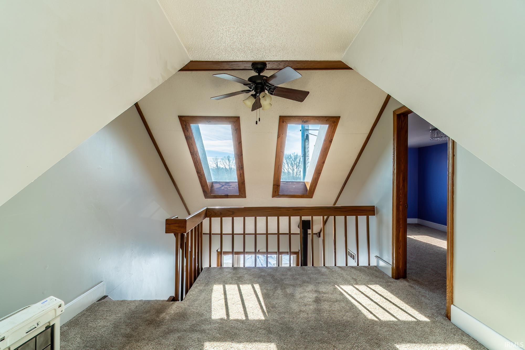 Bonus room featuring carpet floors, vaulted ceiling, a skylight, a textured ceiling, and ceiling fan