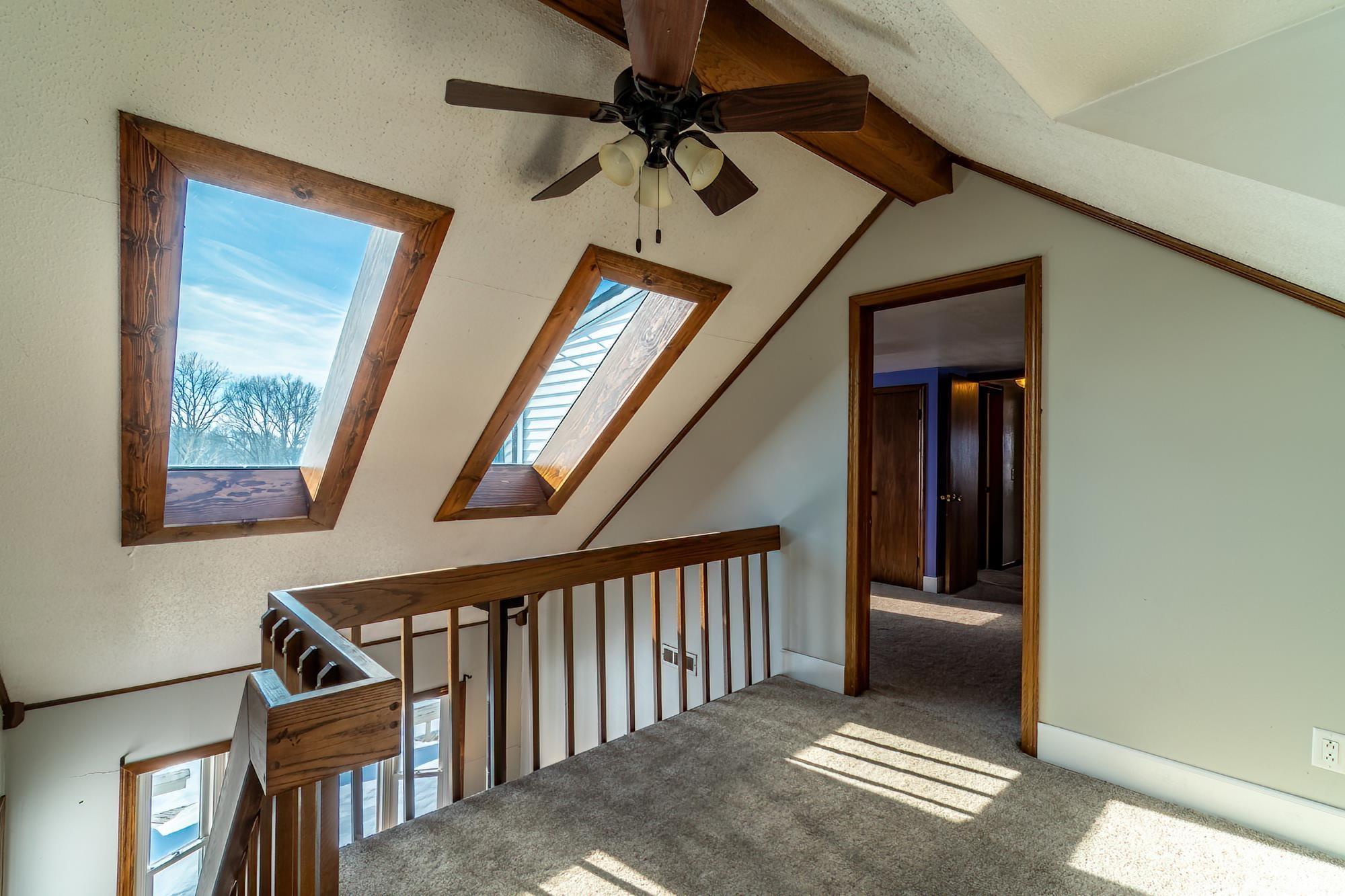 Hallway with a skylight, lofted ceiling, and carpet