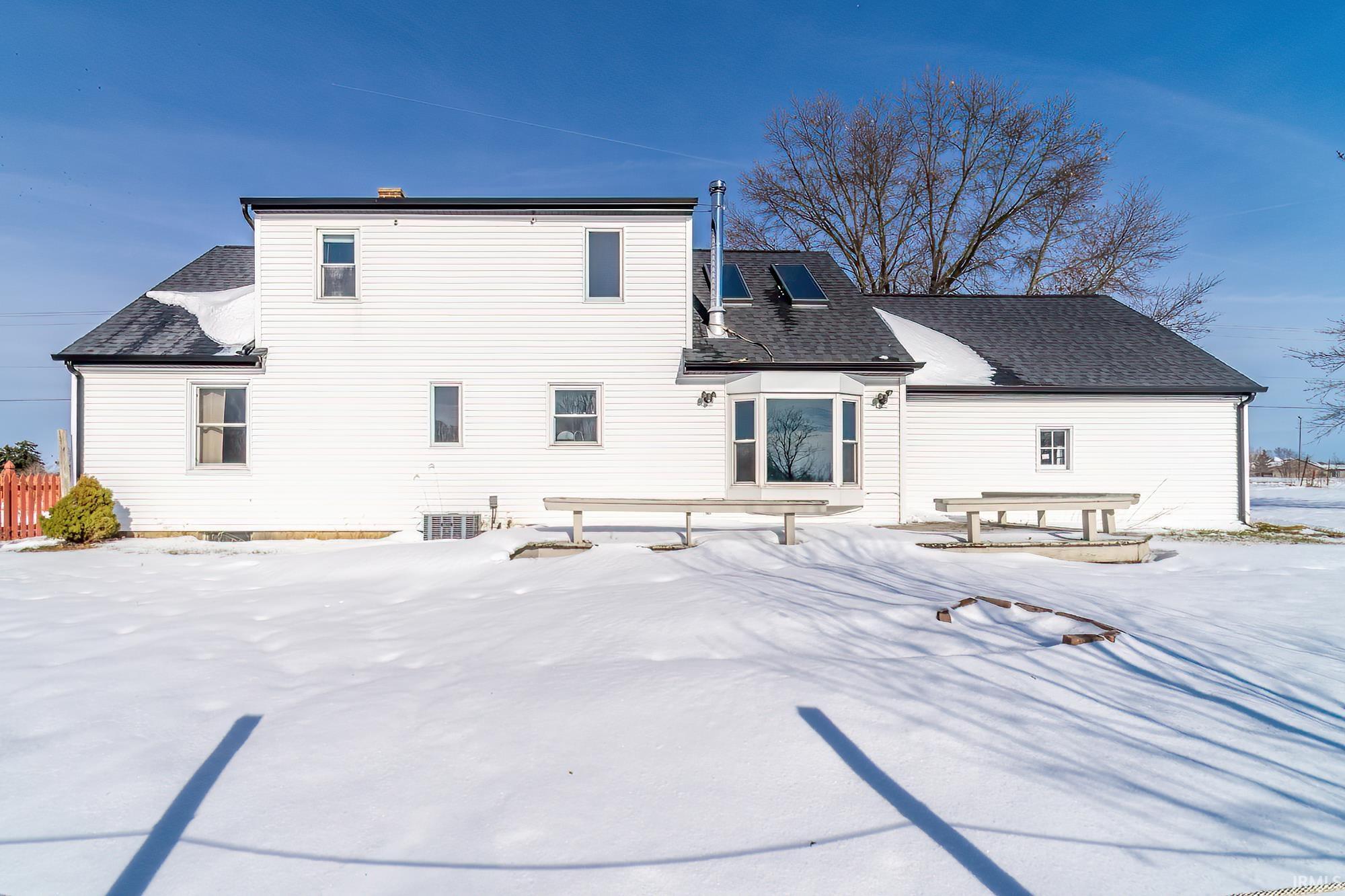 Snow covered rear of property with a shingled roof