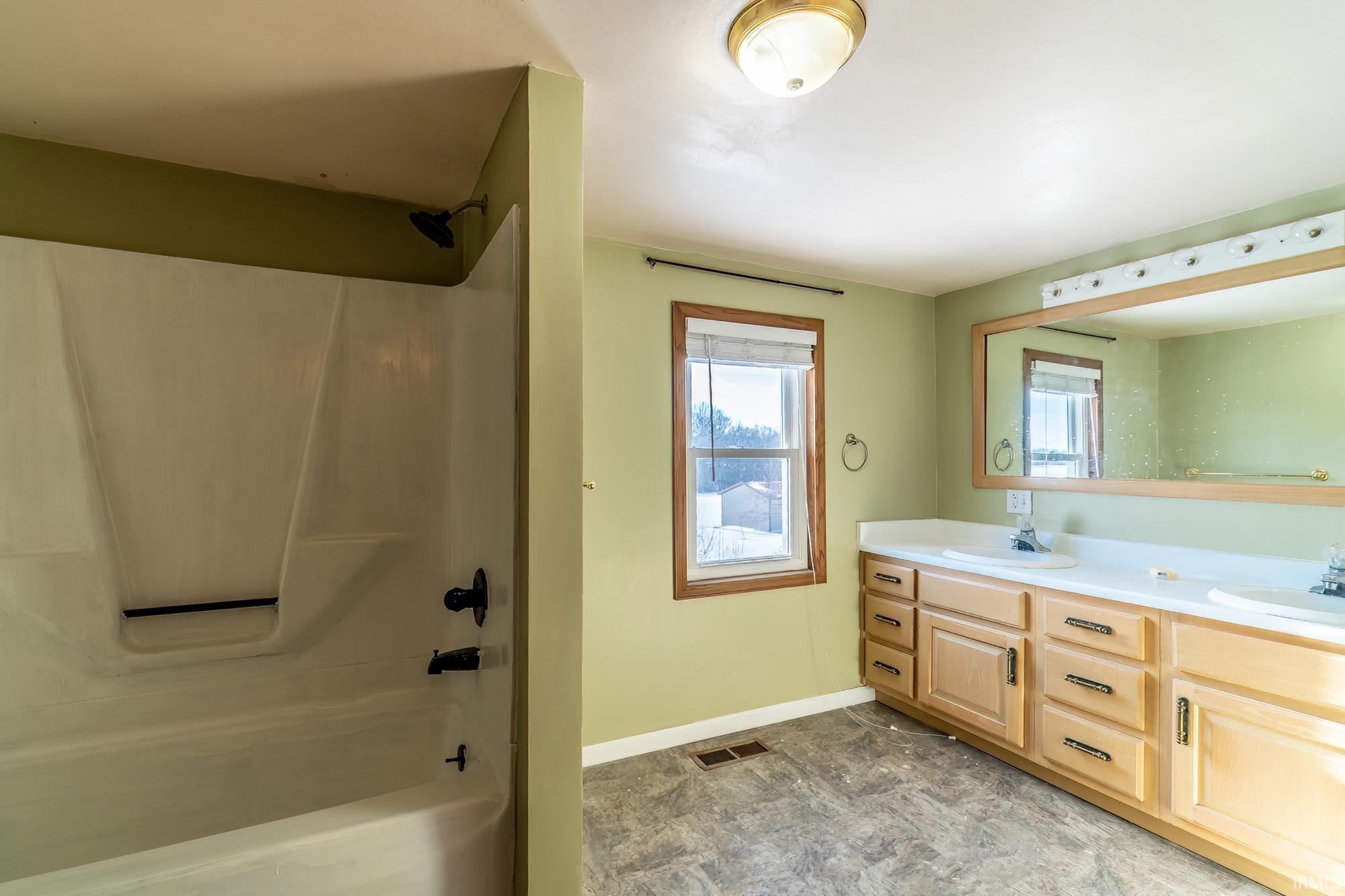 Bathroom with double vanity and bathtub / shower combination