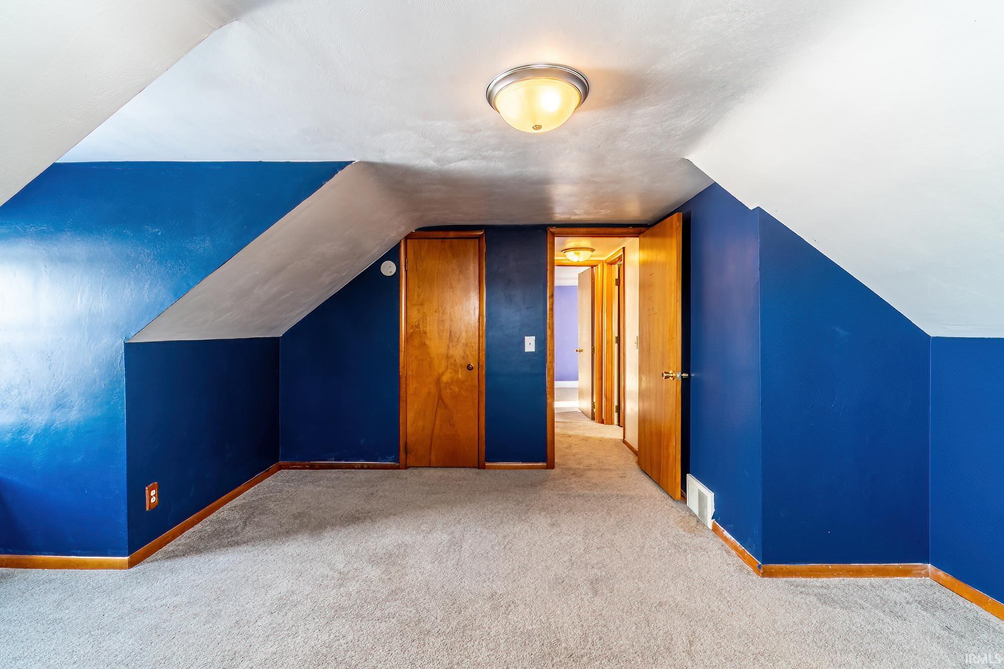 Additional living space with carpet flooring and vaulted ceiling