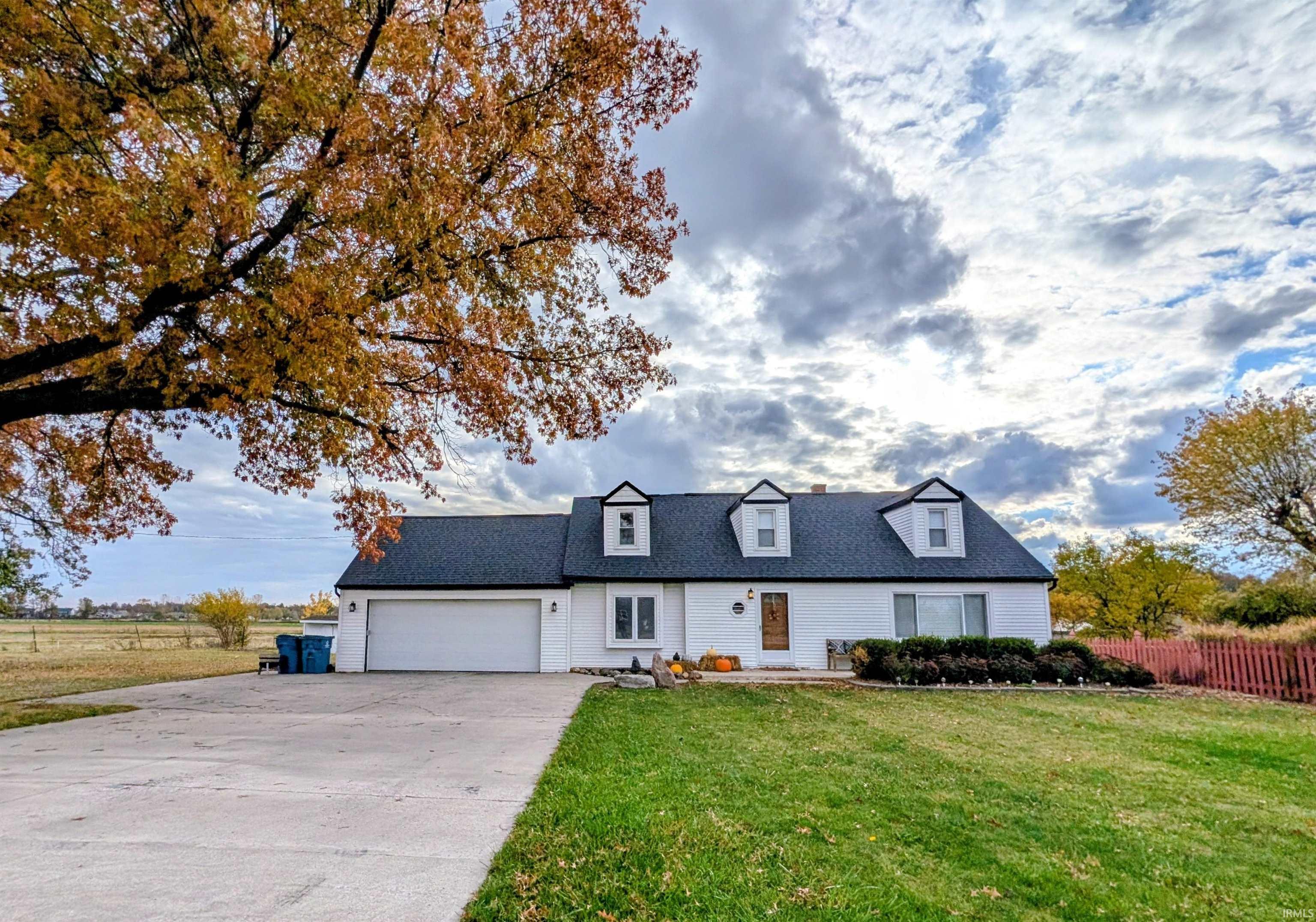 New england style home with driveway, an attached garage, and a shingled roof