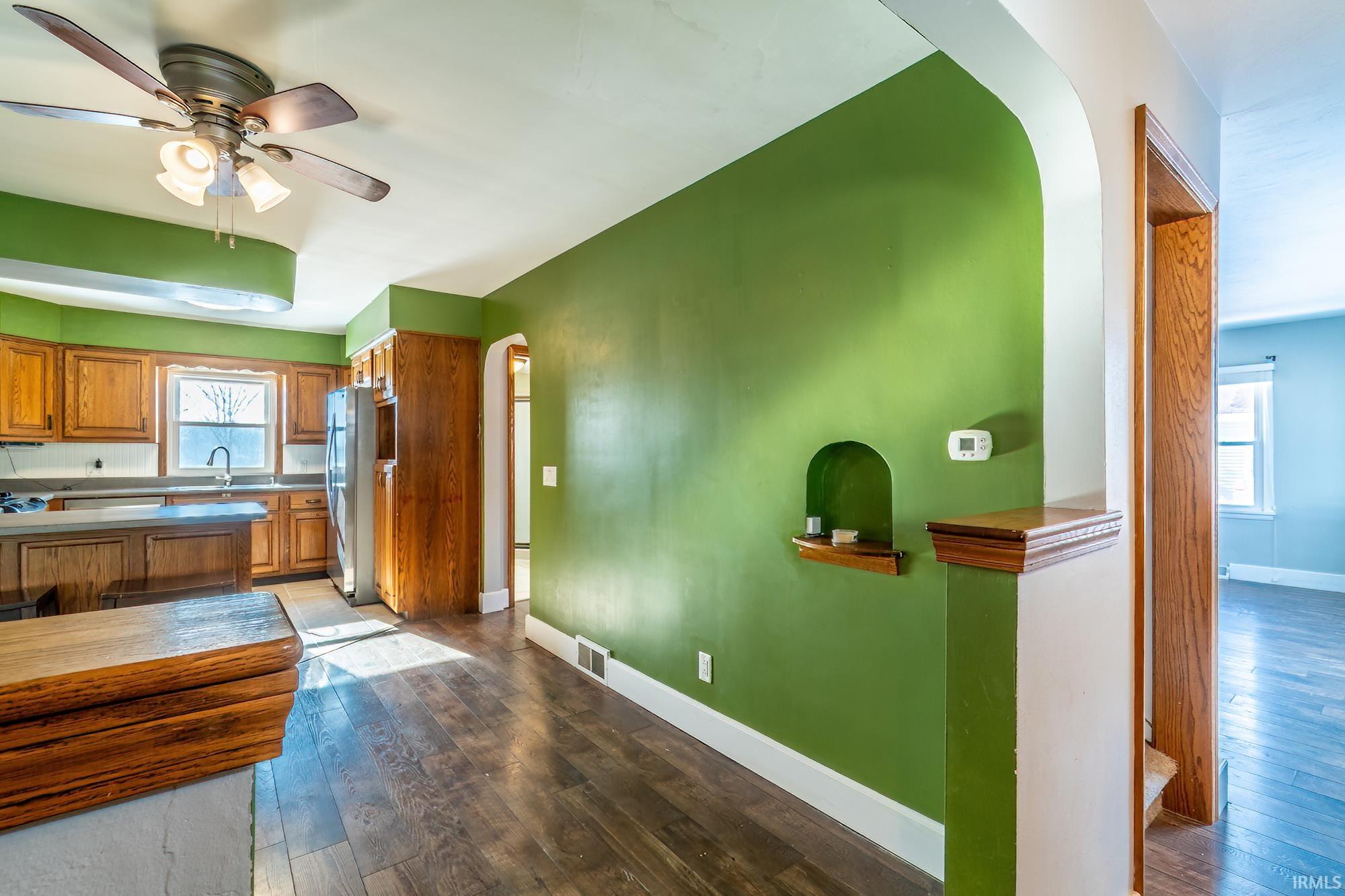 Kitchen featuring healthy amount of natural light, arched walkways, and dark wood-style flooring