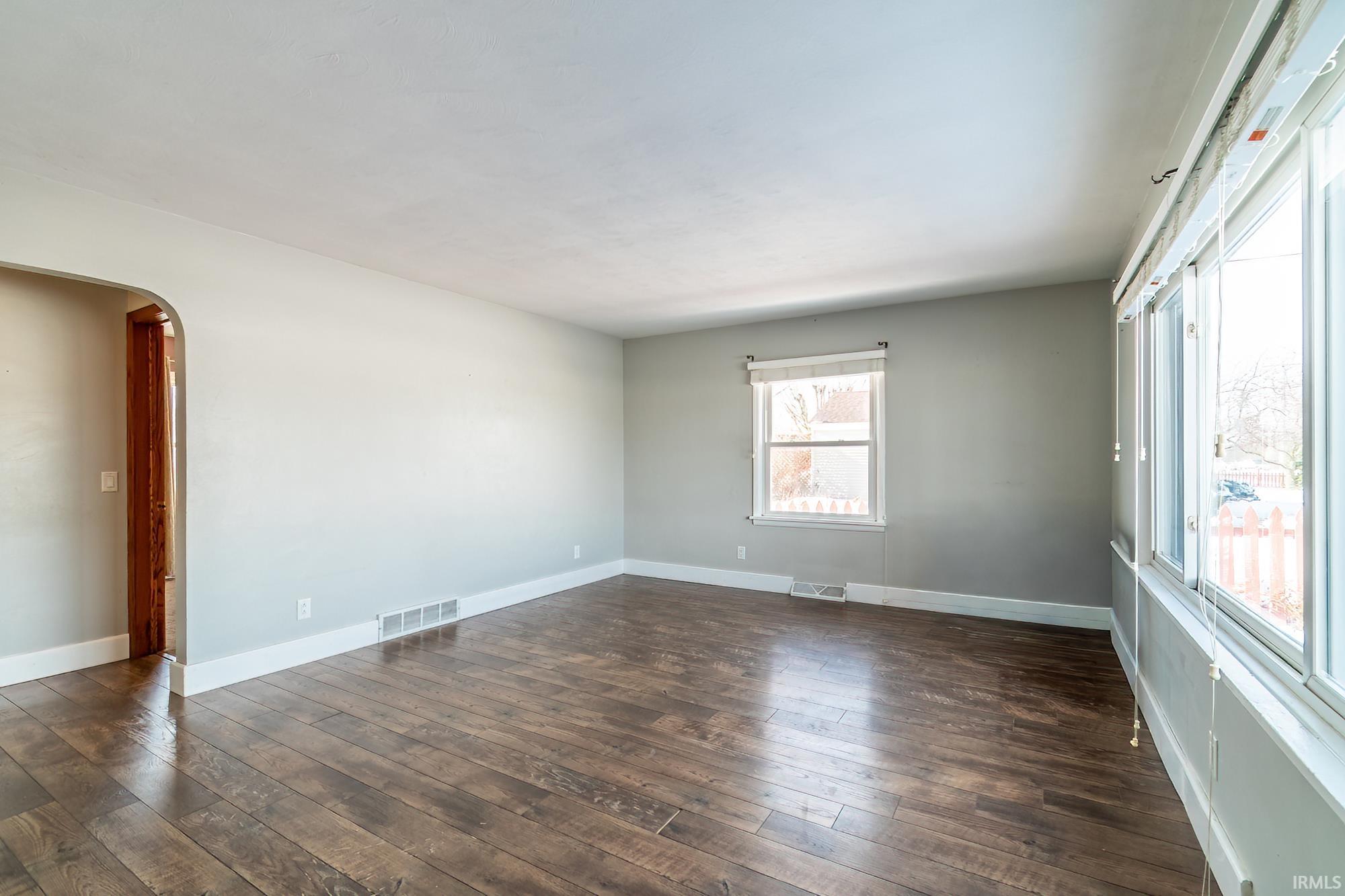 Unfurnished room featuring arched walkways and dark wood finished floors