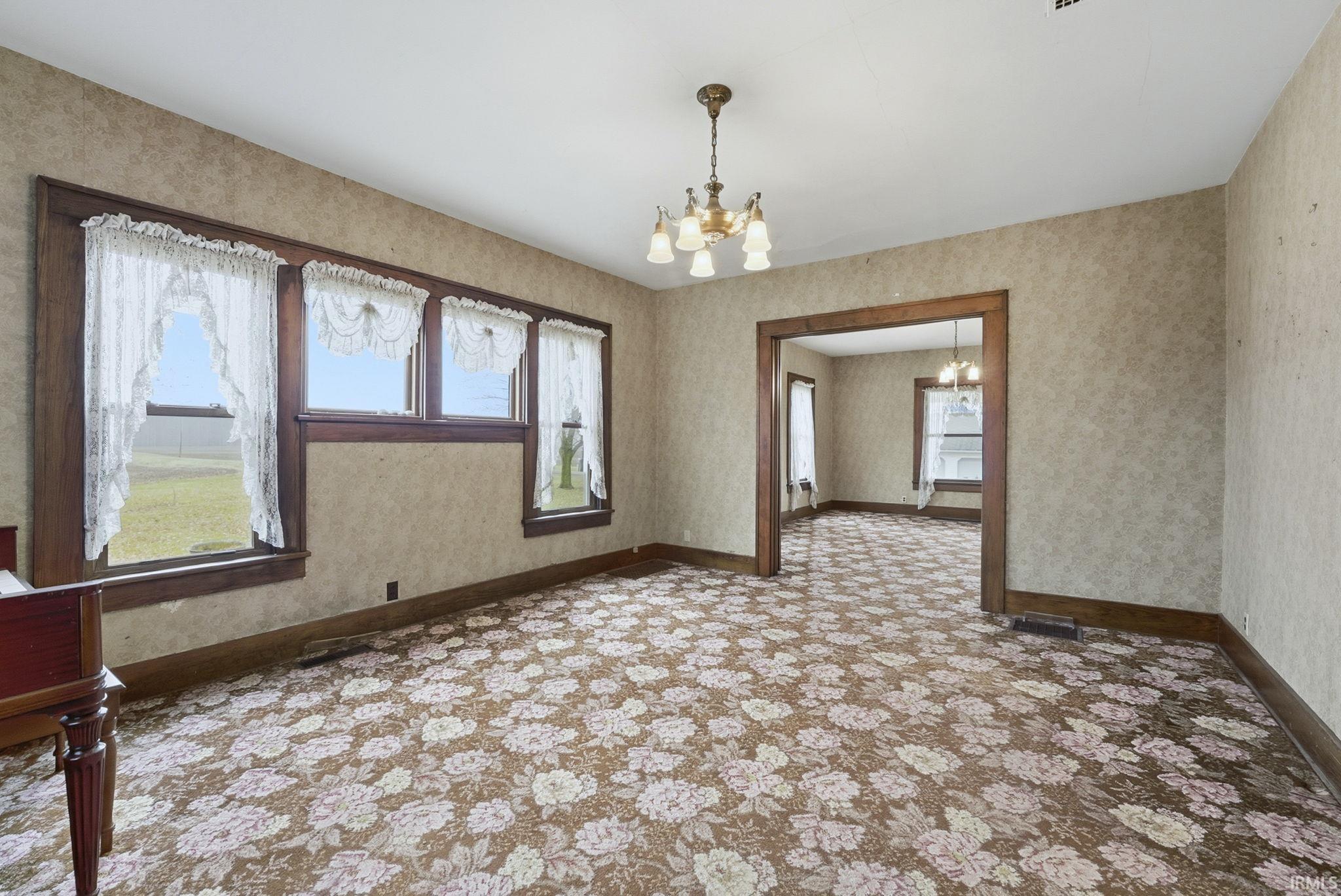 Empty room featuring a chandelier and wallpapered walls