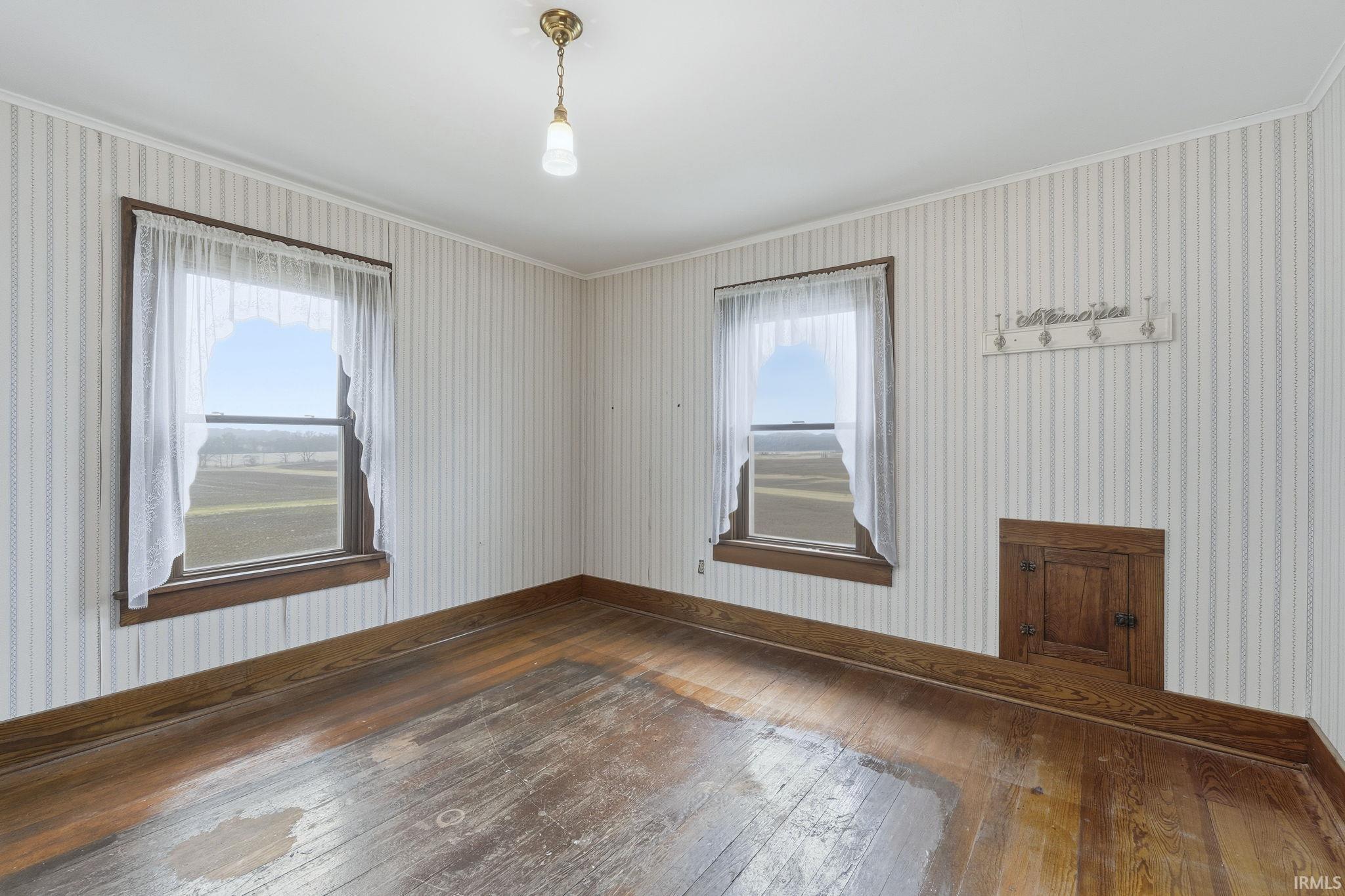 Unfurnished room with wallpapered walls, hardwood / wood-style flooring, and crown molding