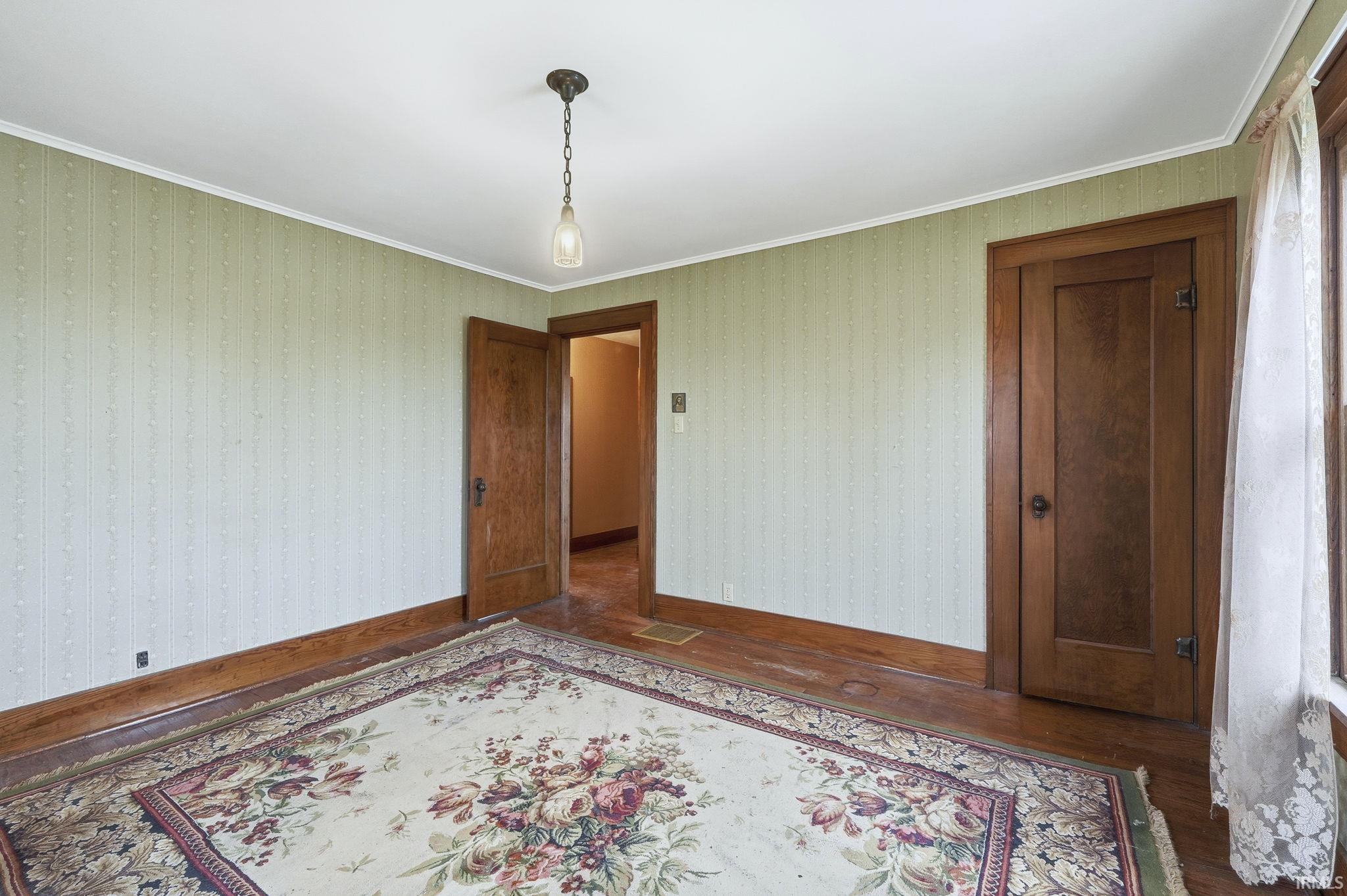 Unfurnished room with wood finished floors and ornamental molding