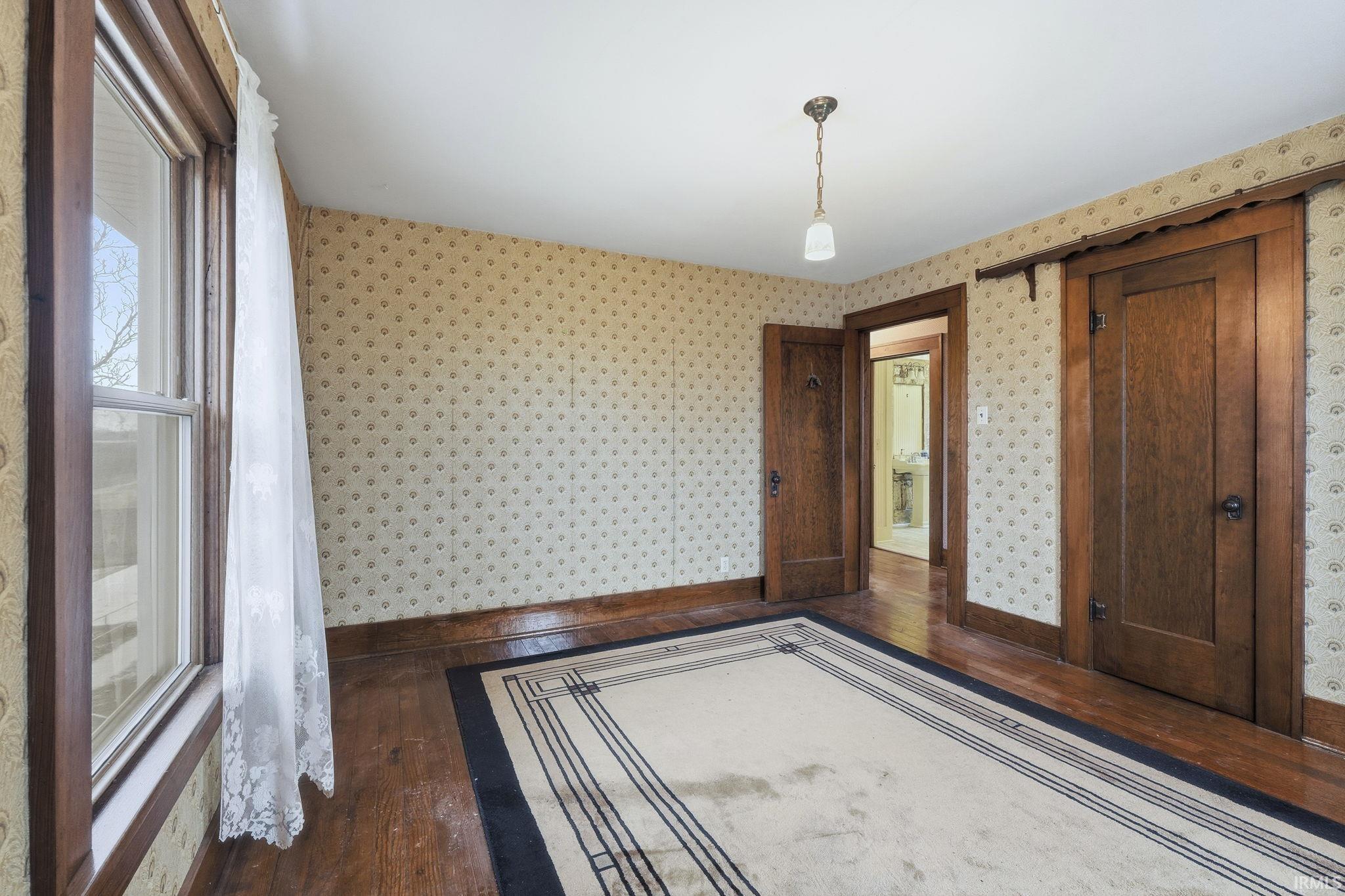 Unfurnished bedroom with dark wood-type flooring and baseboards