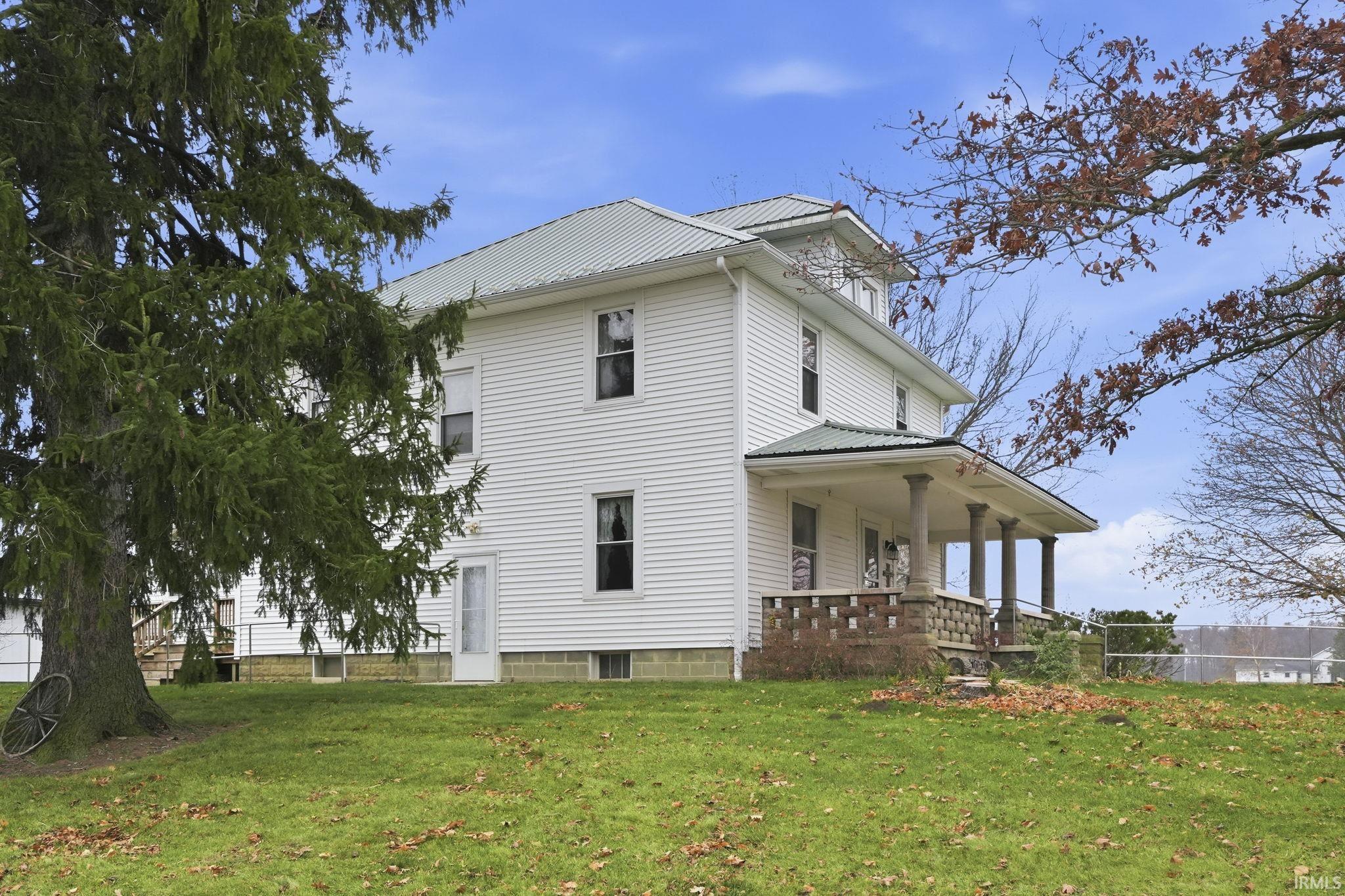View of side of property with a metal roof, a yard, and covered porch