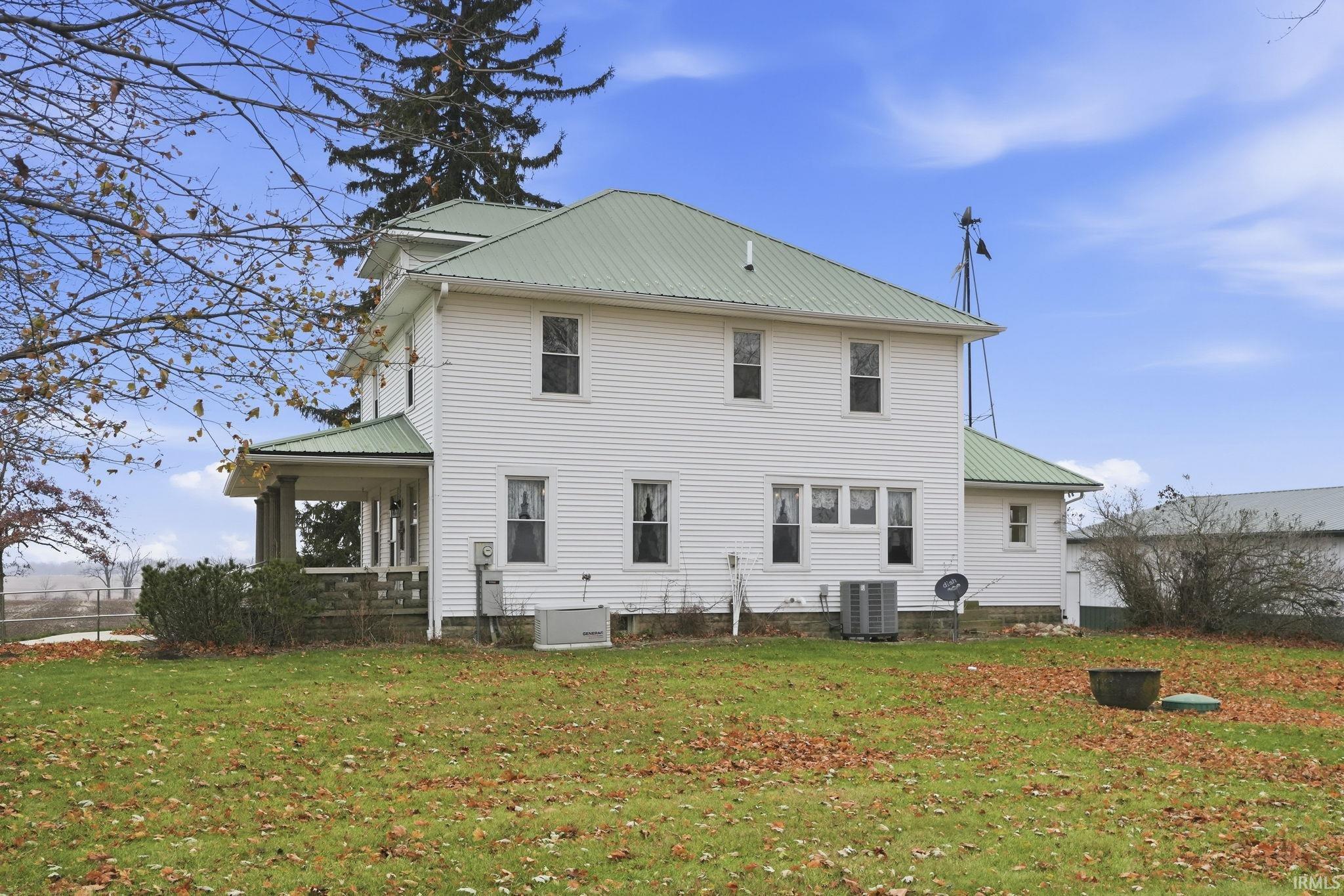 Back of property with a metal roof and a lawn
