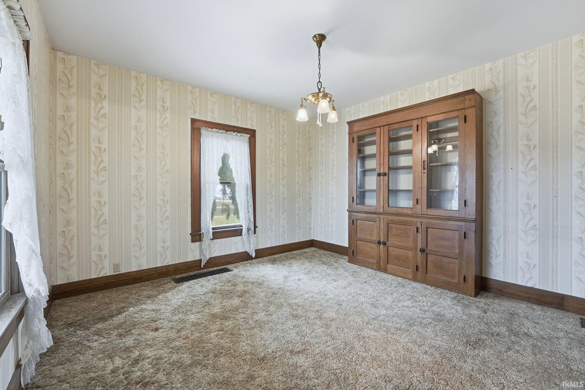 Unfurnished dining area with a chandelier, carpet, and wallpapered walls