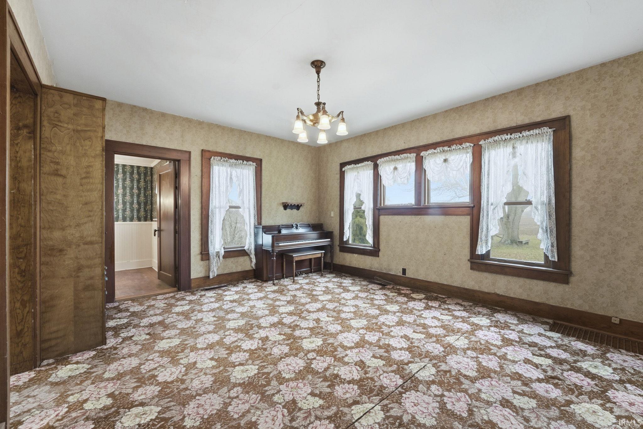 Unfurnished room featuring wallpapered walls and a chandelier