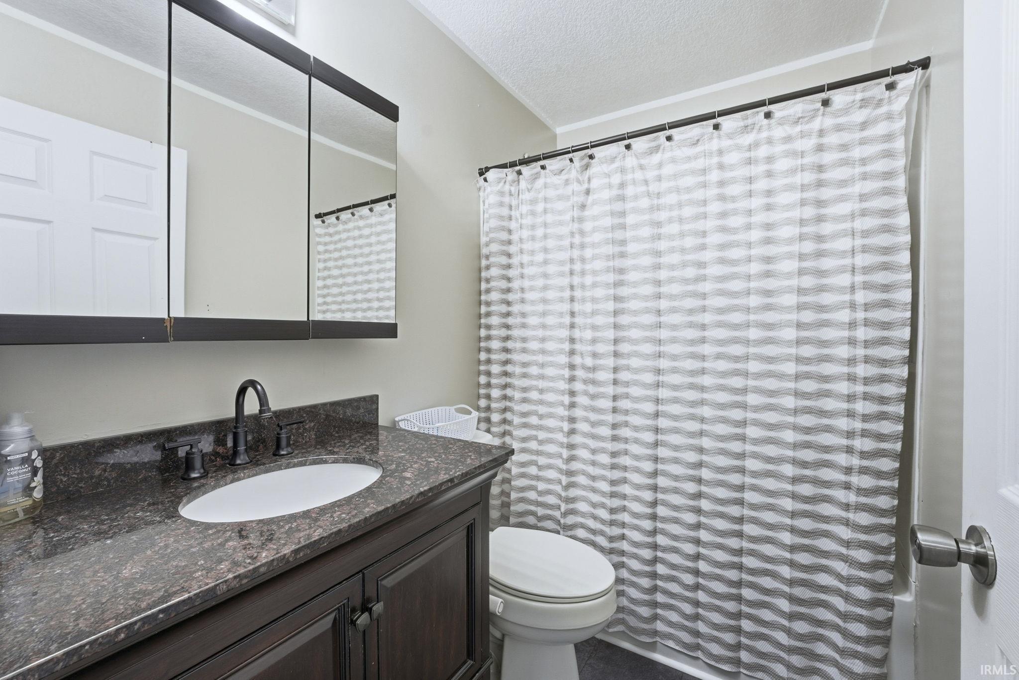 Full bathroom with a textured ceiling, a shower with shower curtain, and vanity