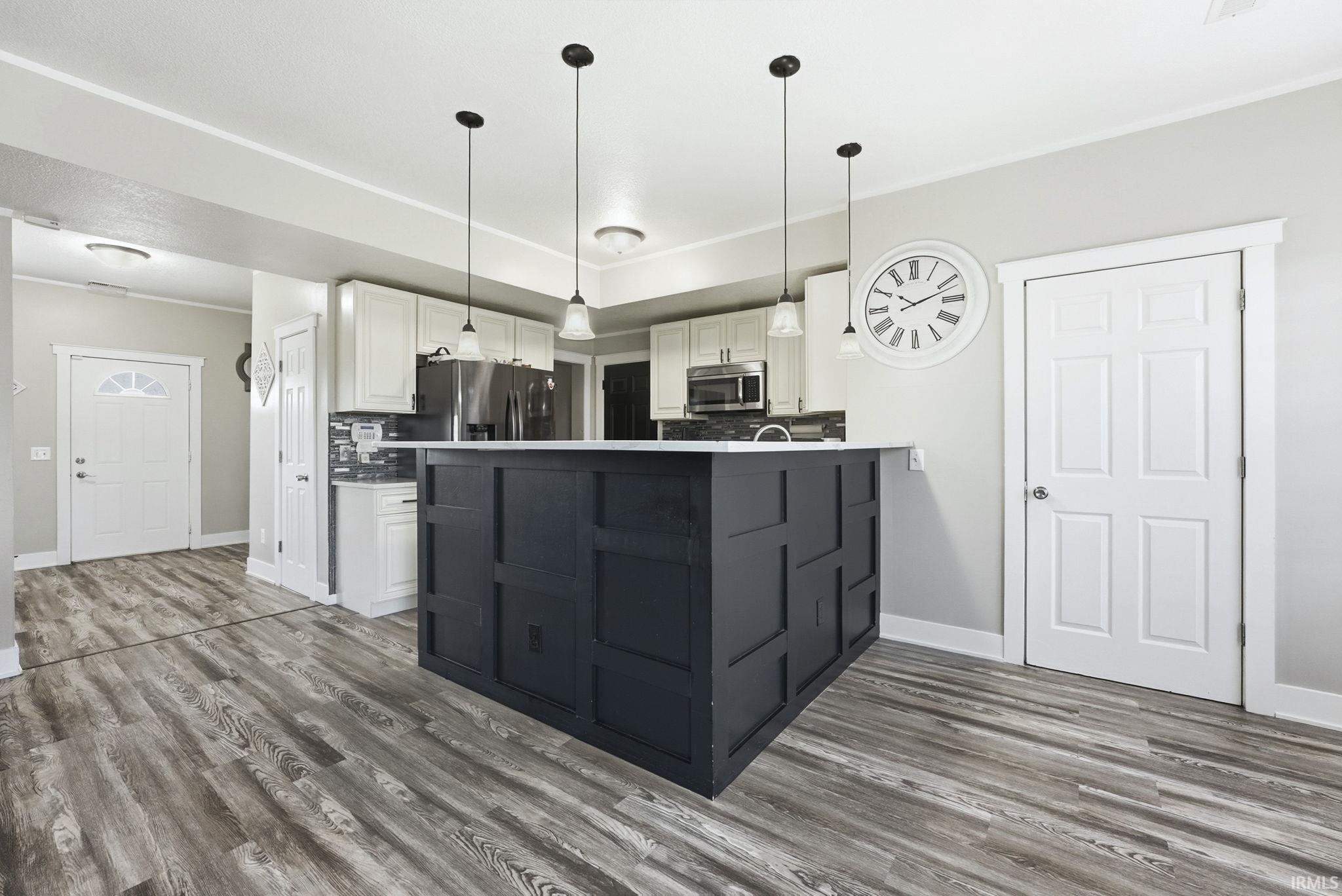 Kitchen with white cabinetry, tasteful backsplash, pendant lighting, dark wood-type flooring, and appliances with stainless steel finishes