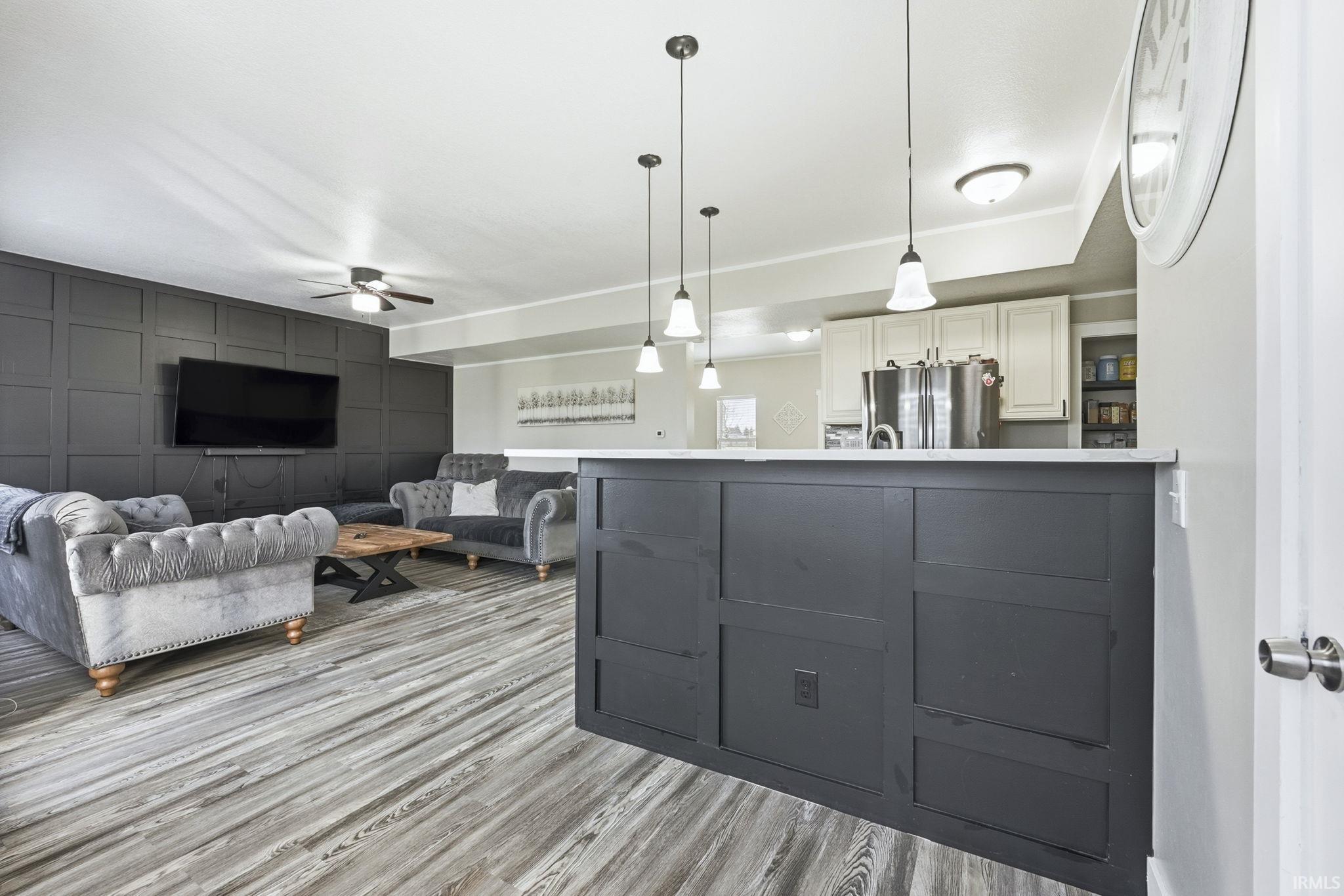 Kitchen featuring decorative light fixtures, ceiling fan, freestanding refrigerator, light countertops, and open floor plan