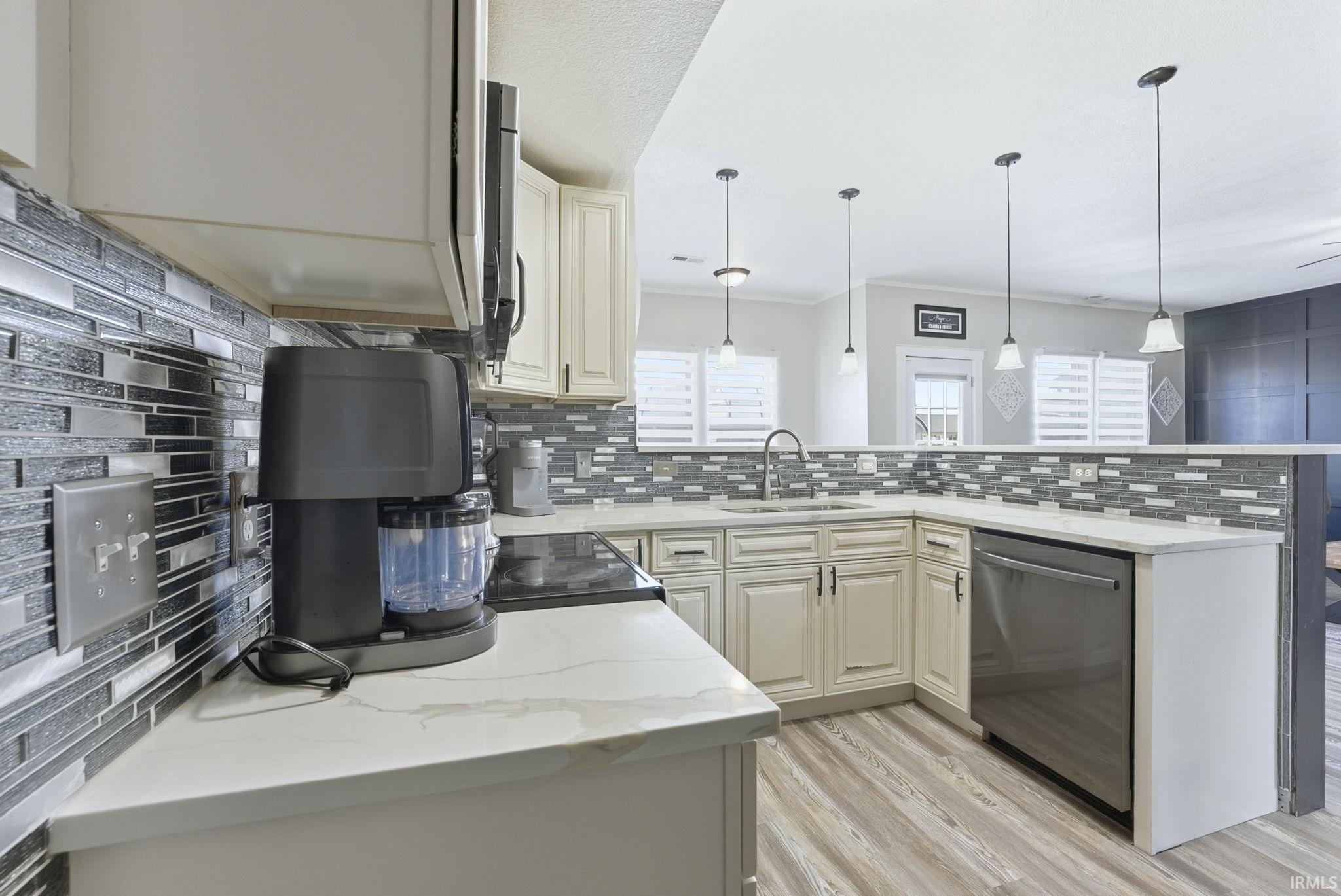 Kitchen with light stone countertops, decorative backsplash, light wood-type flooring, stainless steel dishwasher, and crown molding