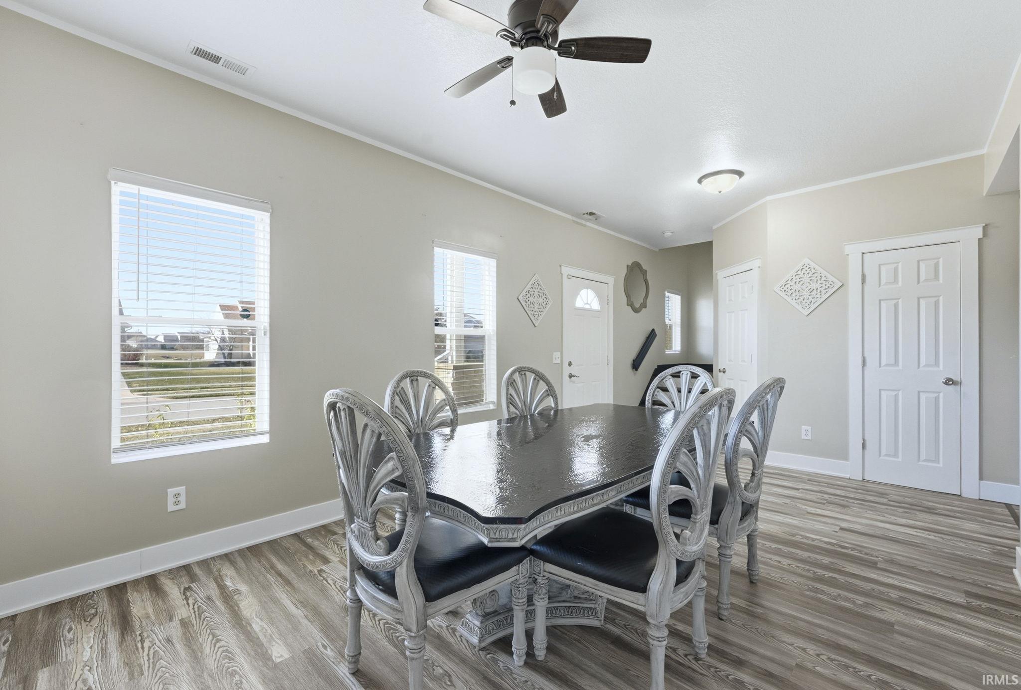 Dining room with light wood-type flooring, crown molding, and ceiling fan