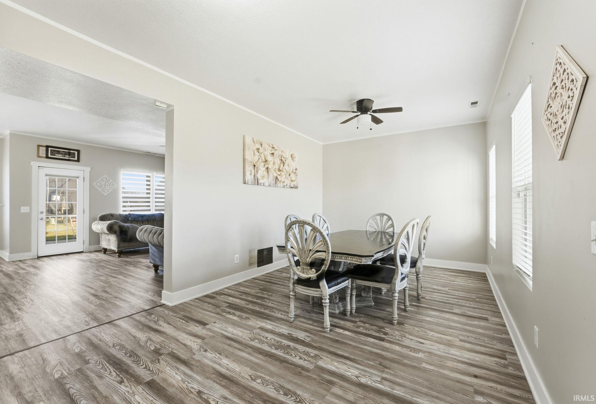 Dining space featuring light wood-style flooring, ceiling fan, and crown molding