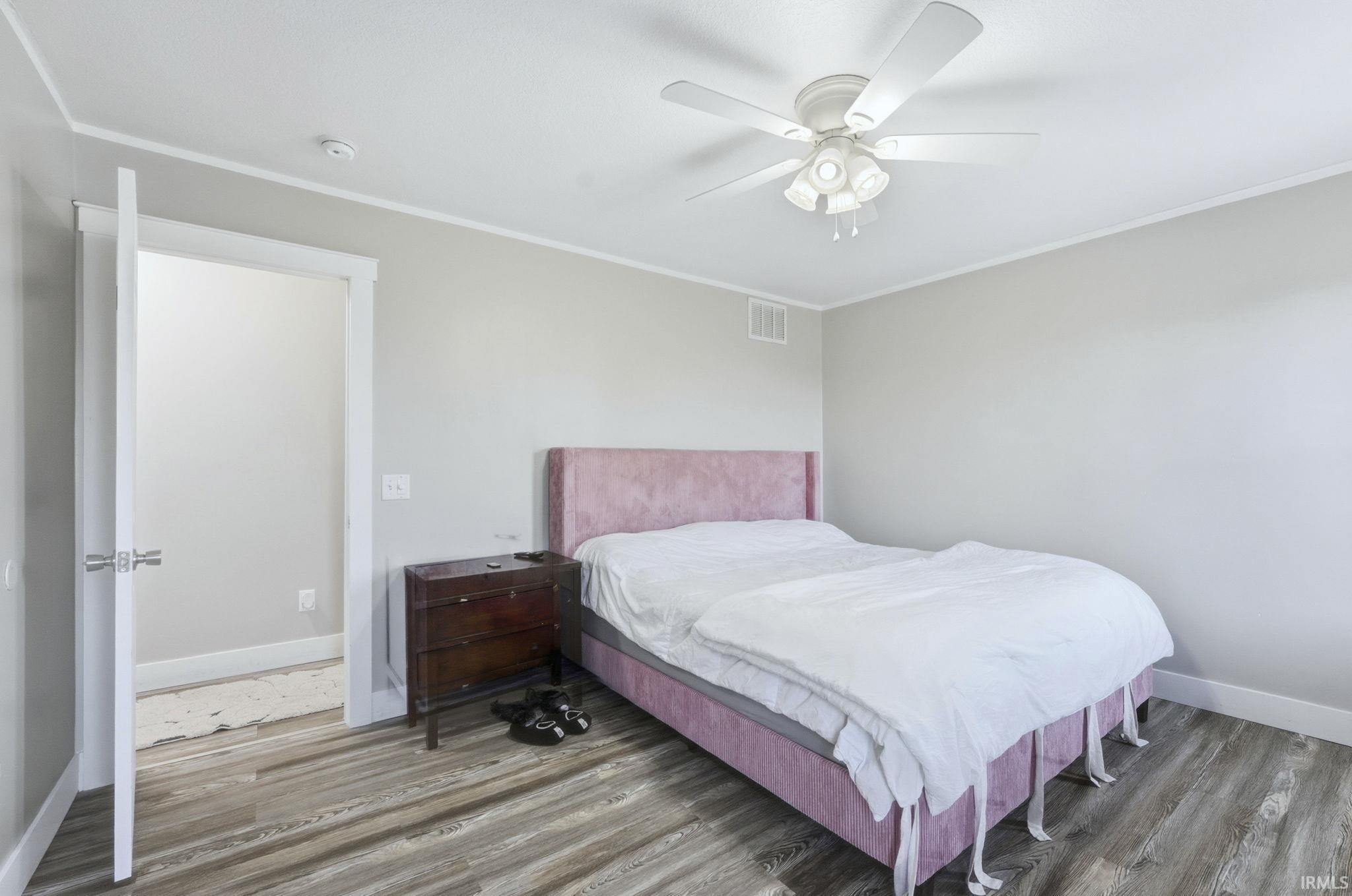 Bedroom featuring wood finished floors, crown molding, and ceiling fan