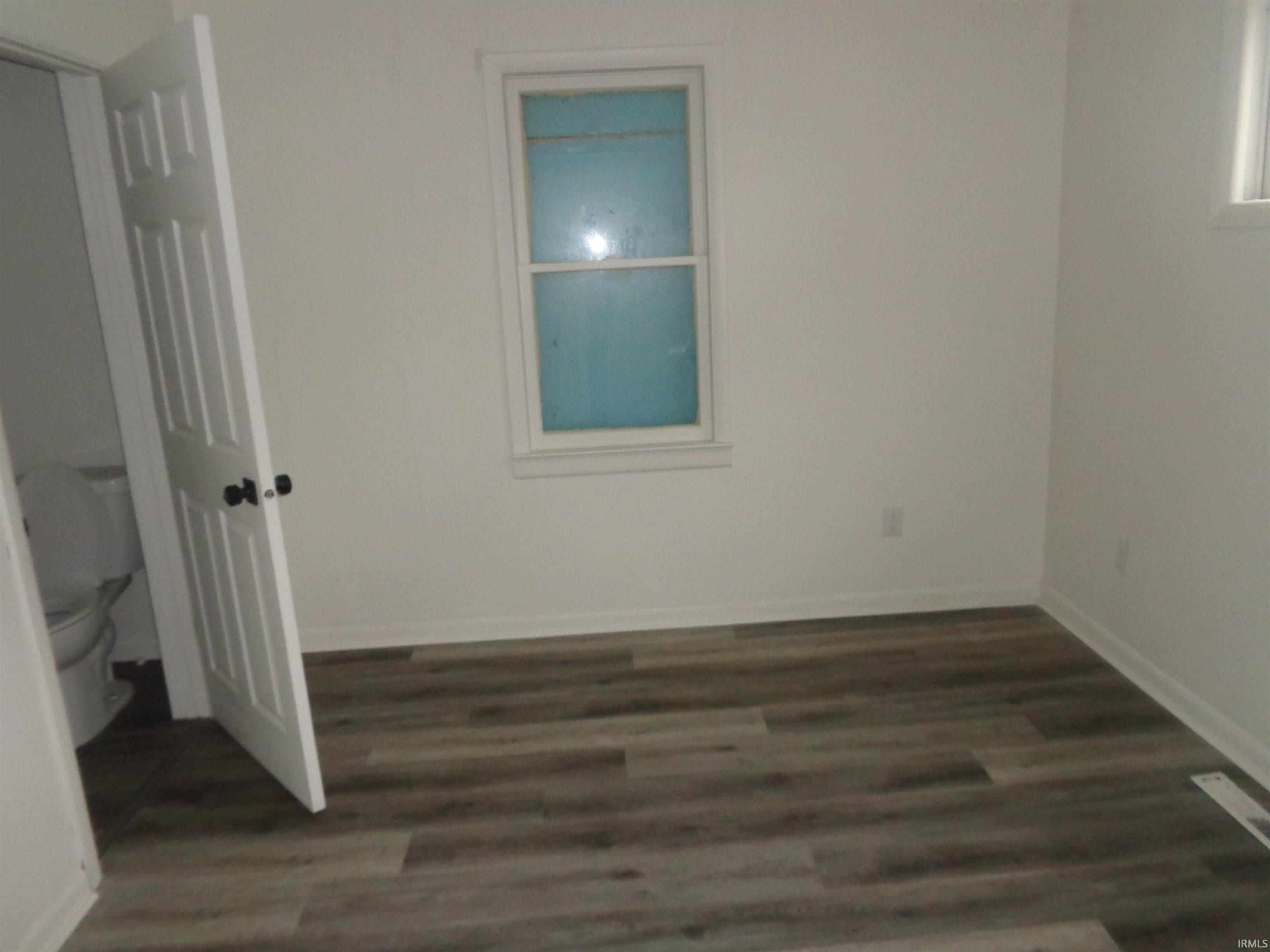 Empty room with dark wood-style floors and baseboards
